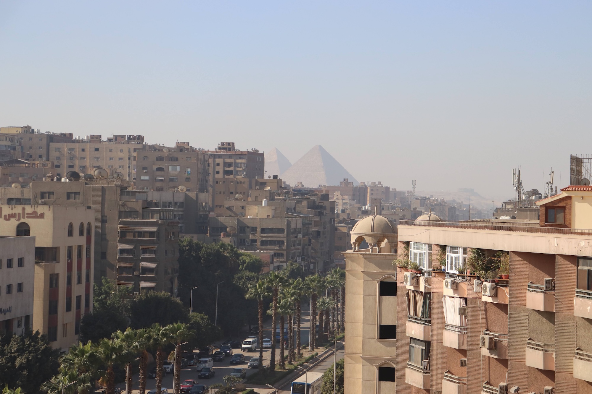 Cairo traffic and buildings with Great Pyramids of Giza visible in background