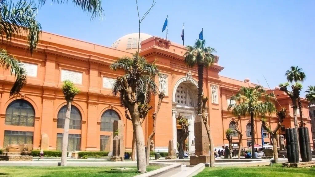 The pink neoclassical facade of the Egyptian Museum at Tahrir Square in Cairo, with the gardens and entrance steps in the foreground