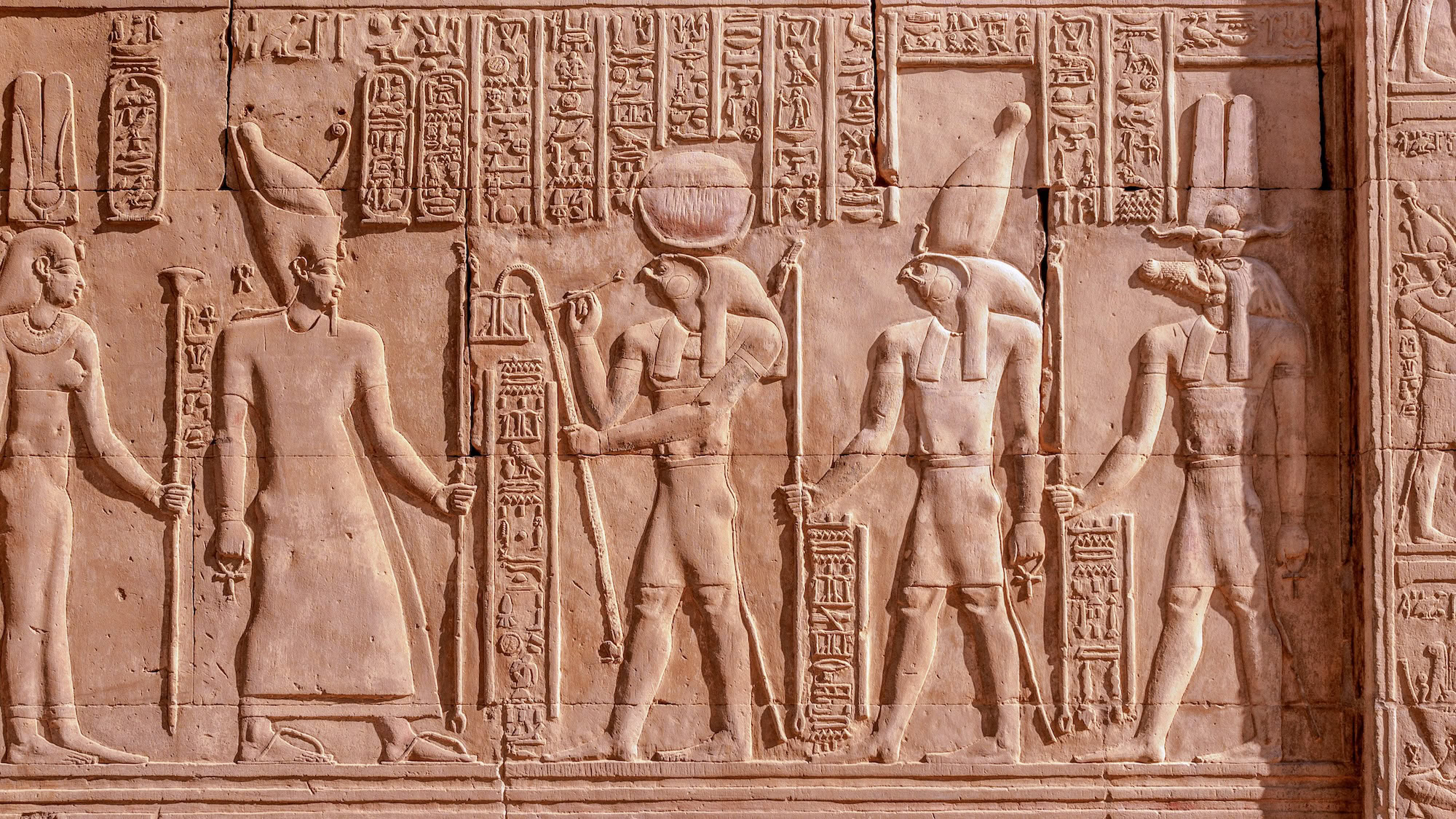 Ancient Egyptian temple wall relief depicting ceremonial scene with pharaoh and deities