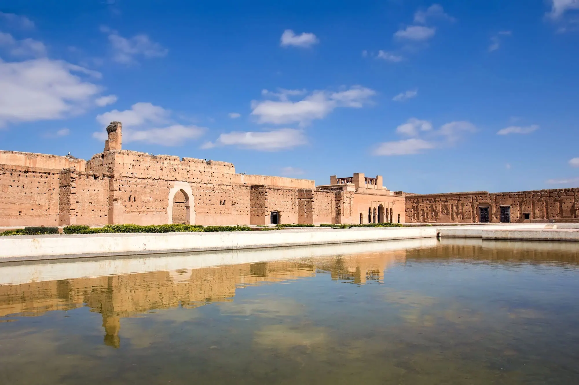 Panoramic view of El Badi Palace ruins with ancient mud brick walls reflected in water pool
