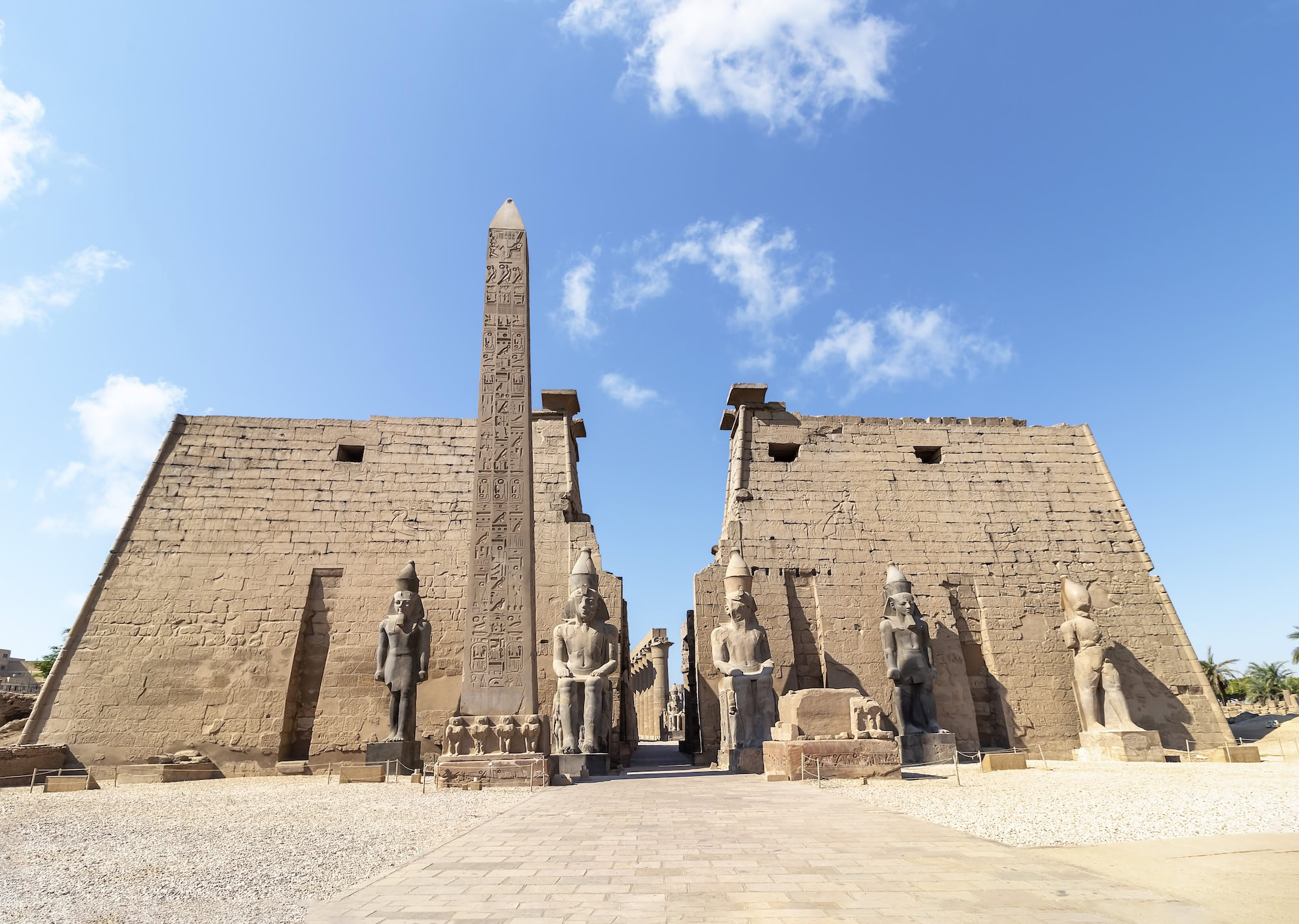 Ancient Luxor Temple entrance with towering obelisk, pharaoh statues, and hieroglyphic walls showcasing Egypt's monumental architecture