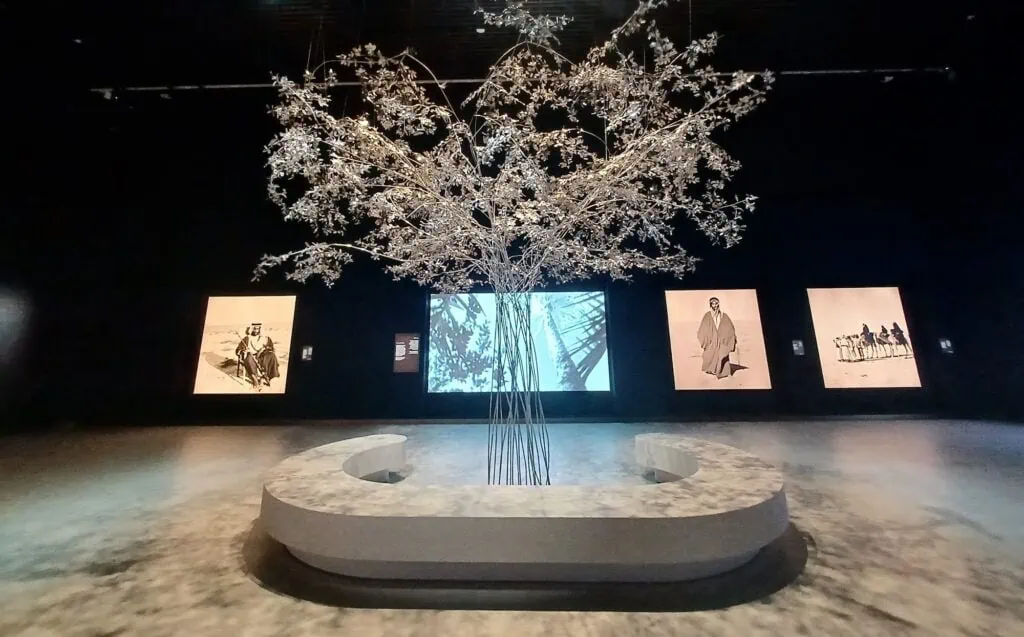 Etihad Museum exhibition hall with central metal tree installation surrounded by curved seating and display panels Dubai