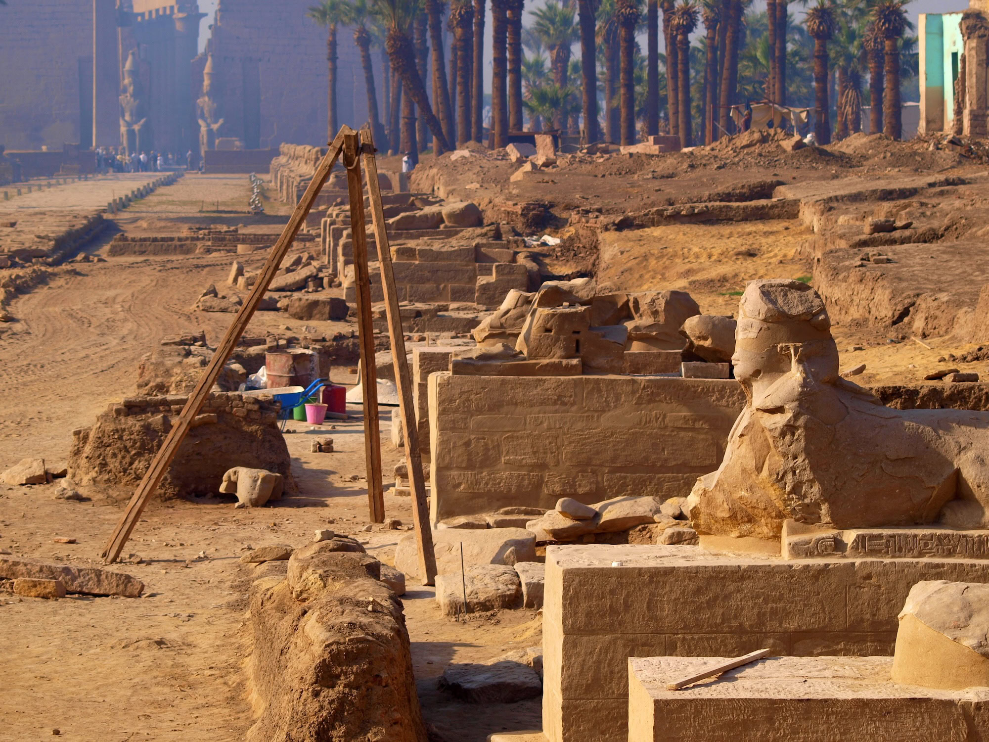 Archaeological excavation site in Egypt with ancient stone ruins and surveying equipment
