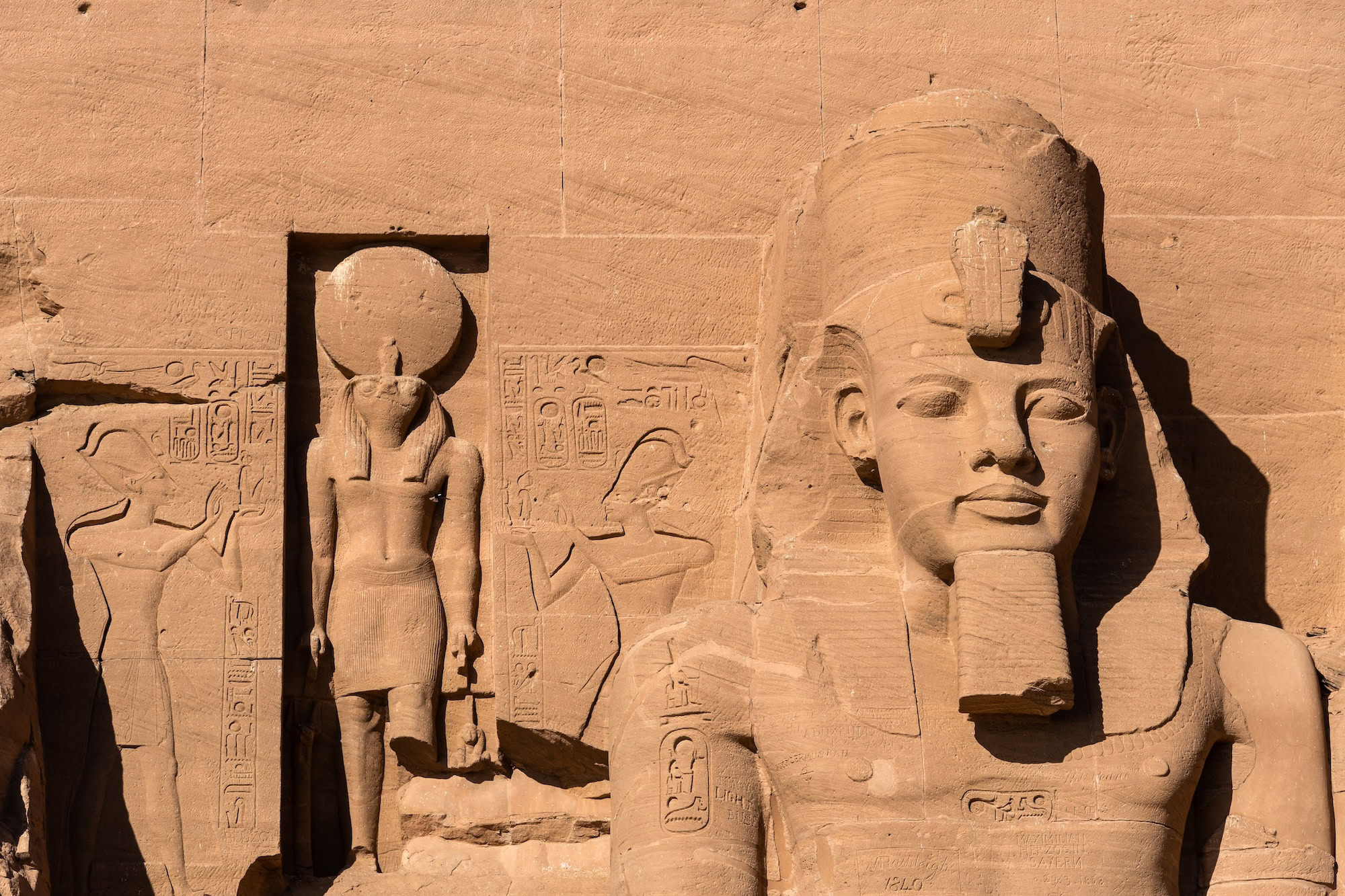 Ancient pharaoh statues and hieroglyphics at Abu Simbel temple facade