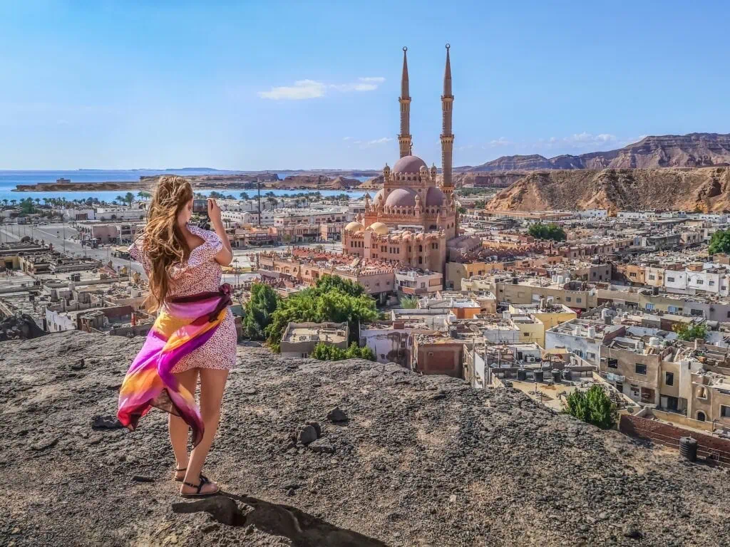 A female traveler photographing the domes and minarets of Al Sahaba Mosque in Sharm El Sheikh's Old Town district