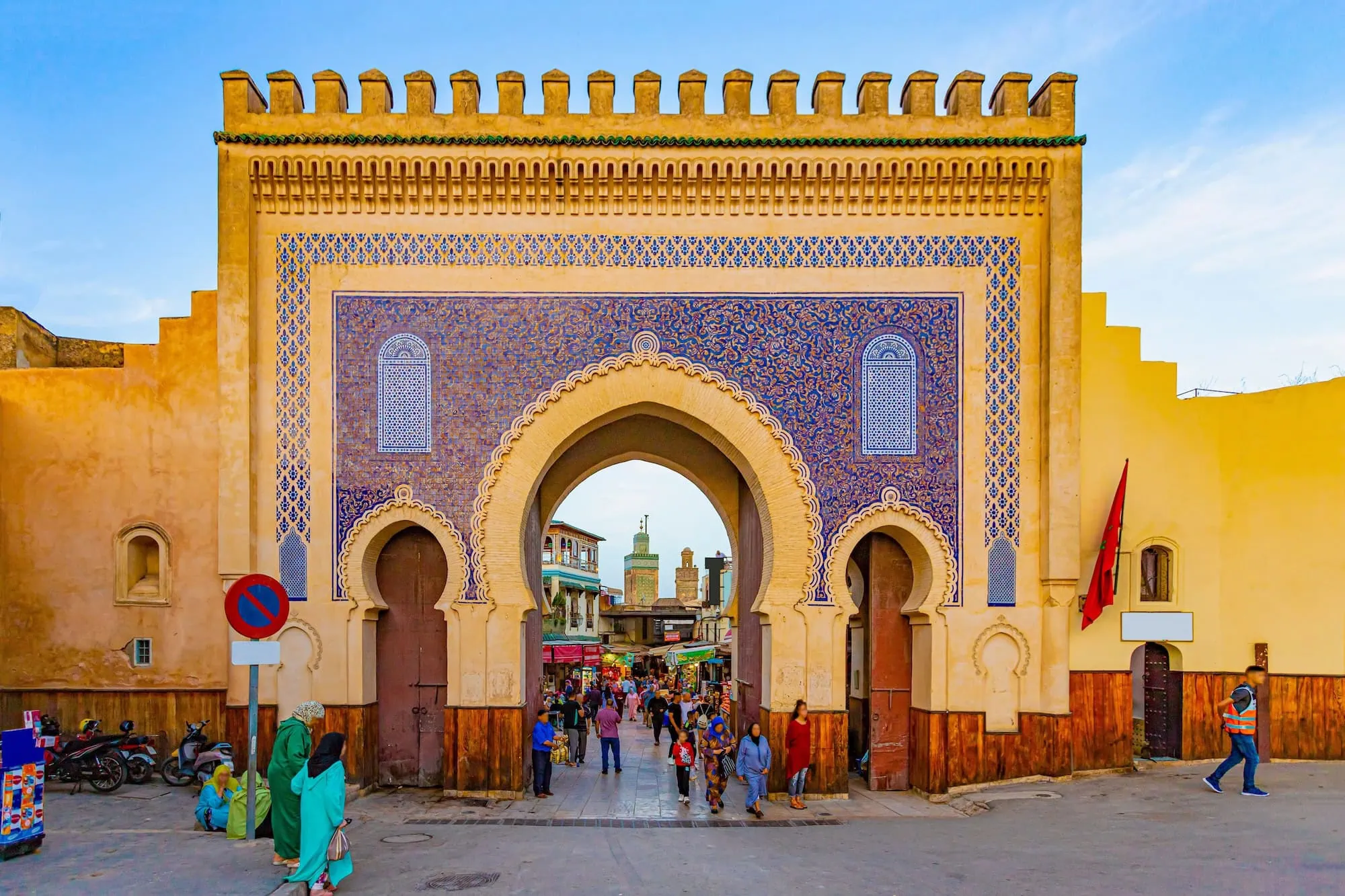 Traditional Moroccan gate entrance to Fez medina with ornate Islamic architecture and people walking through