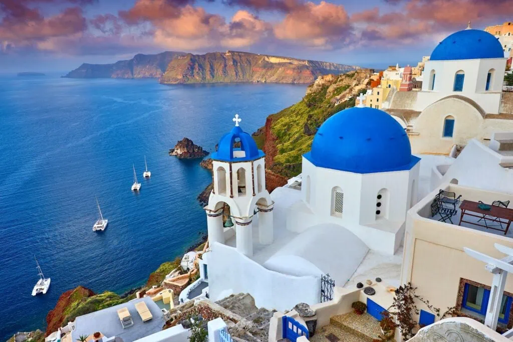 Whitewashed buildings of Fira town tumbling down the volcanic cliffs of Santorini island in soft morning light, Greece.