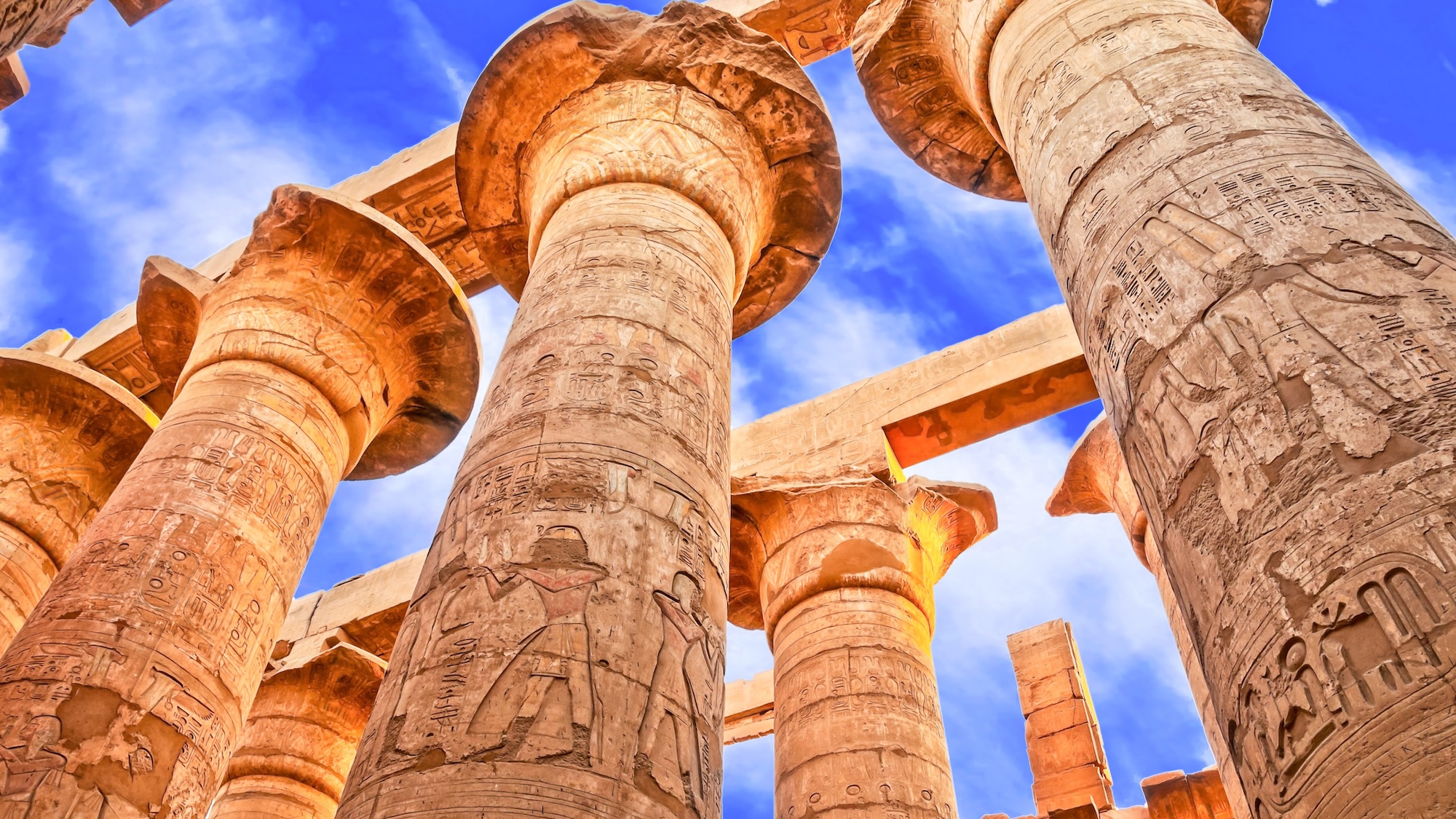 Towering stone columns with papyrus capitals at Karnak Temple showing hieroglyphic carvings