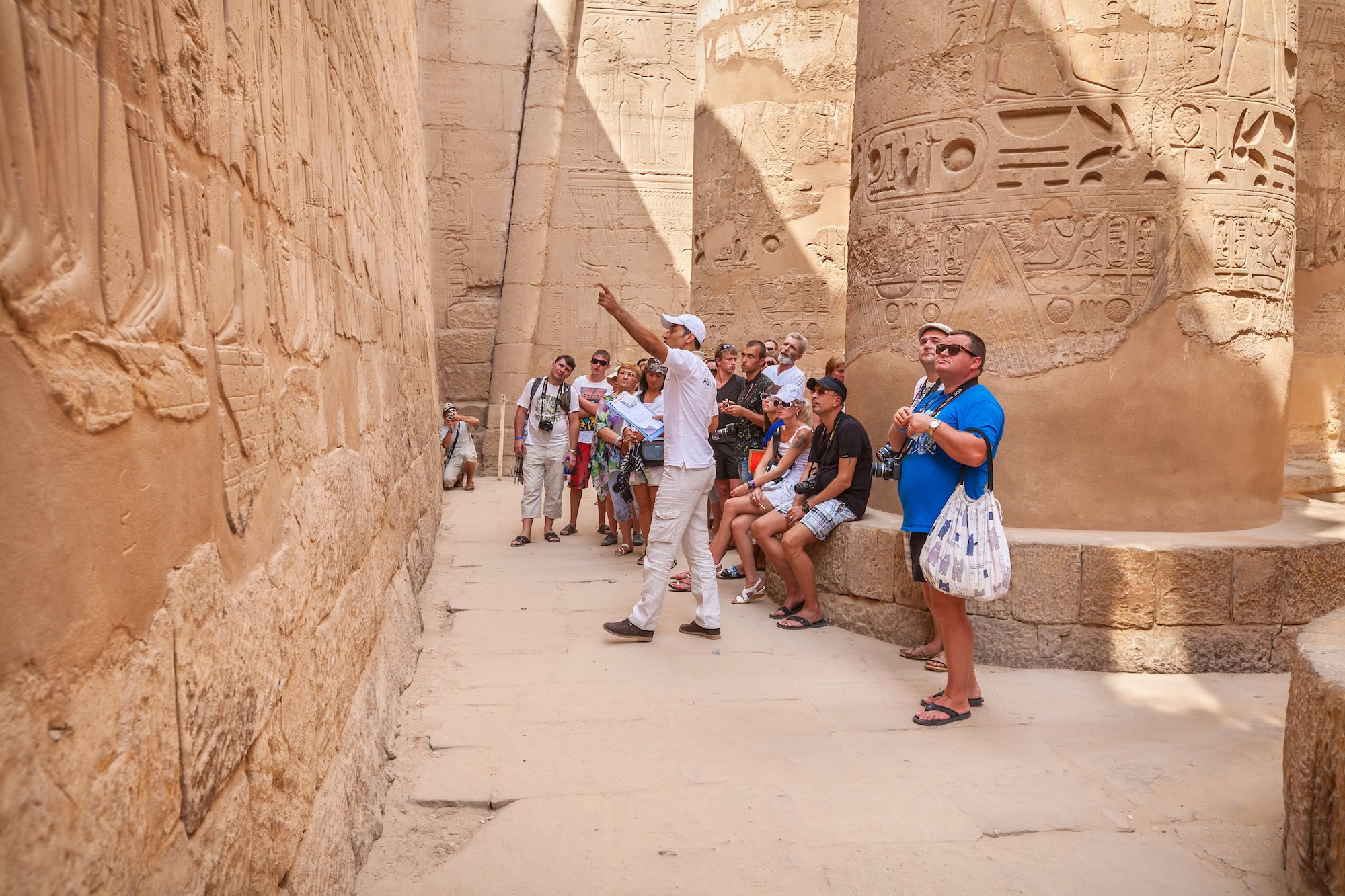 Tour guide explaining hieroglyphs to tourists in ancient Egyptian temple