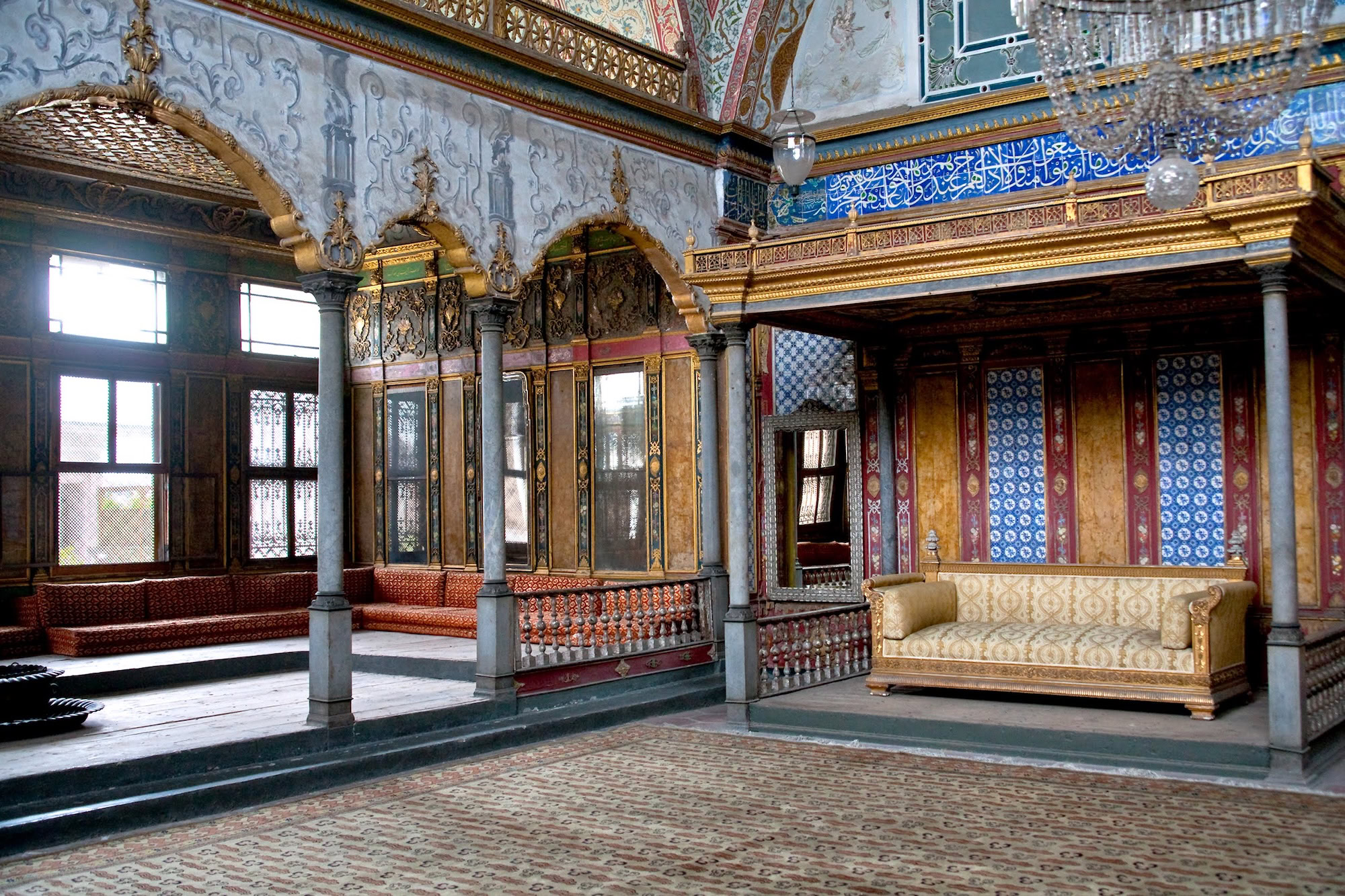 Ornate Ottoman interior of Topkapi Palace with decorative sofa, marble columns and Islamic calligraphy