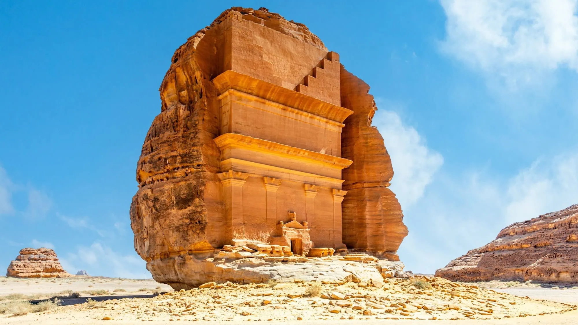Qasr al-Farid tomb at Hegra archaeological site in AlUla, Saudi Arabia — a four-columned Nabataean rock-cut facade carved into a single sandstone outcrop, left unfinished in the lower section - Egypt and Saudi Arabia Tours