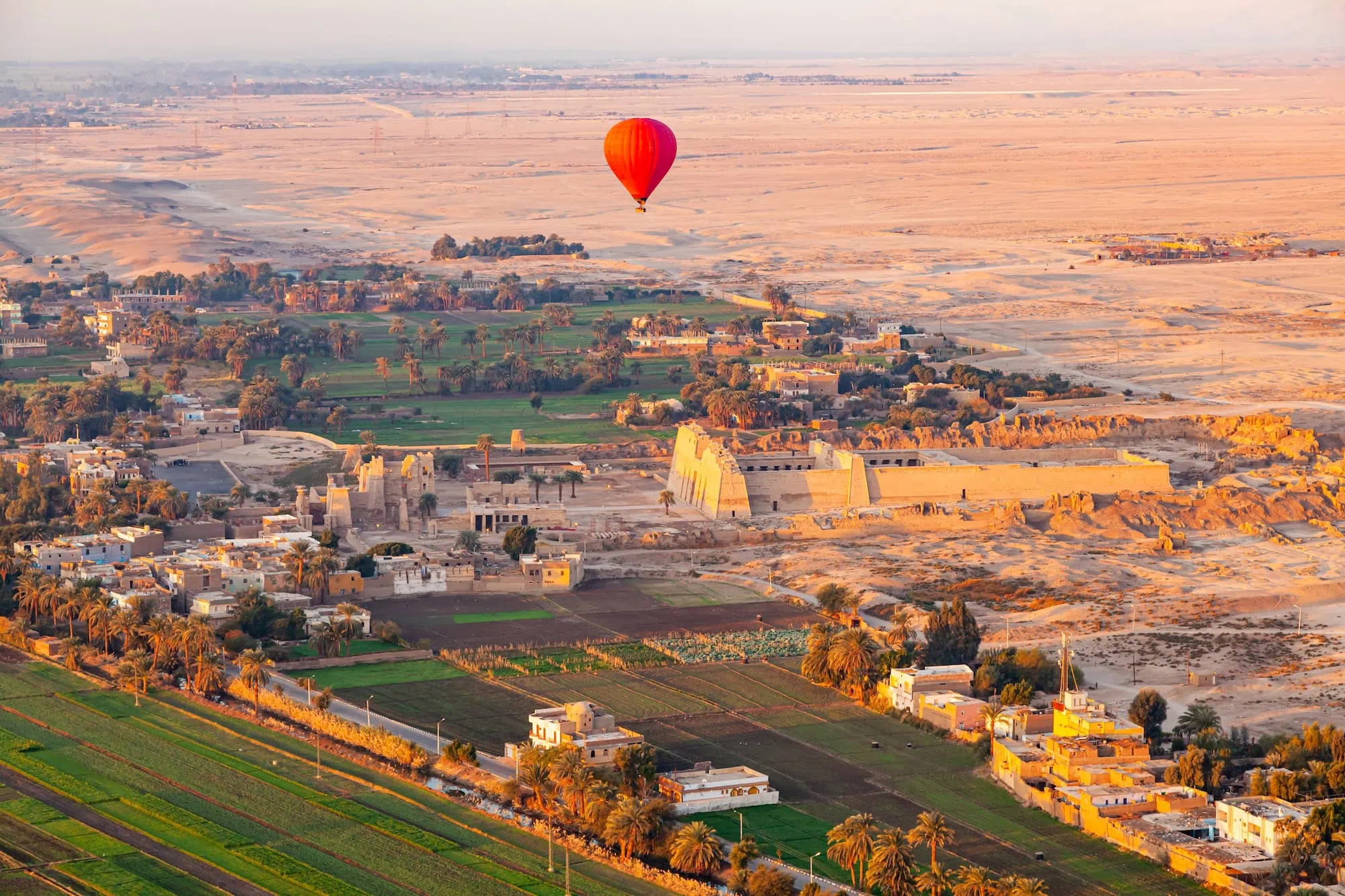 Hot air balloon flying over ancient Egyptian temples and archaeological sites in Luxor valley