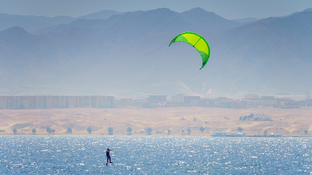 Kite surfer riding the Red Sea with a green kite