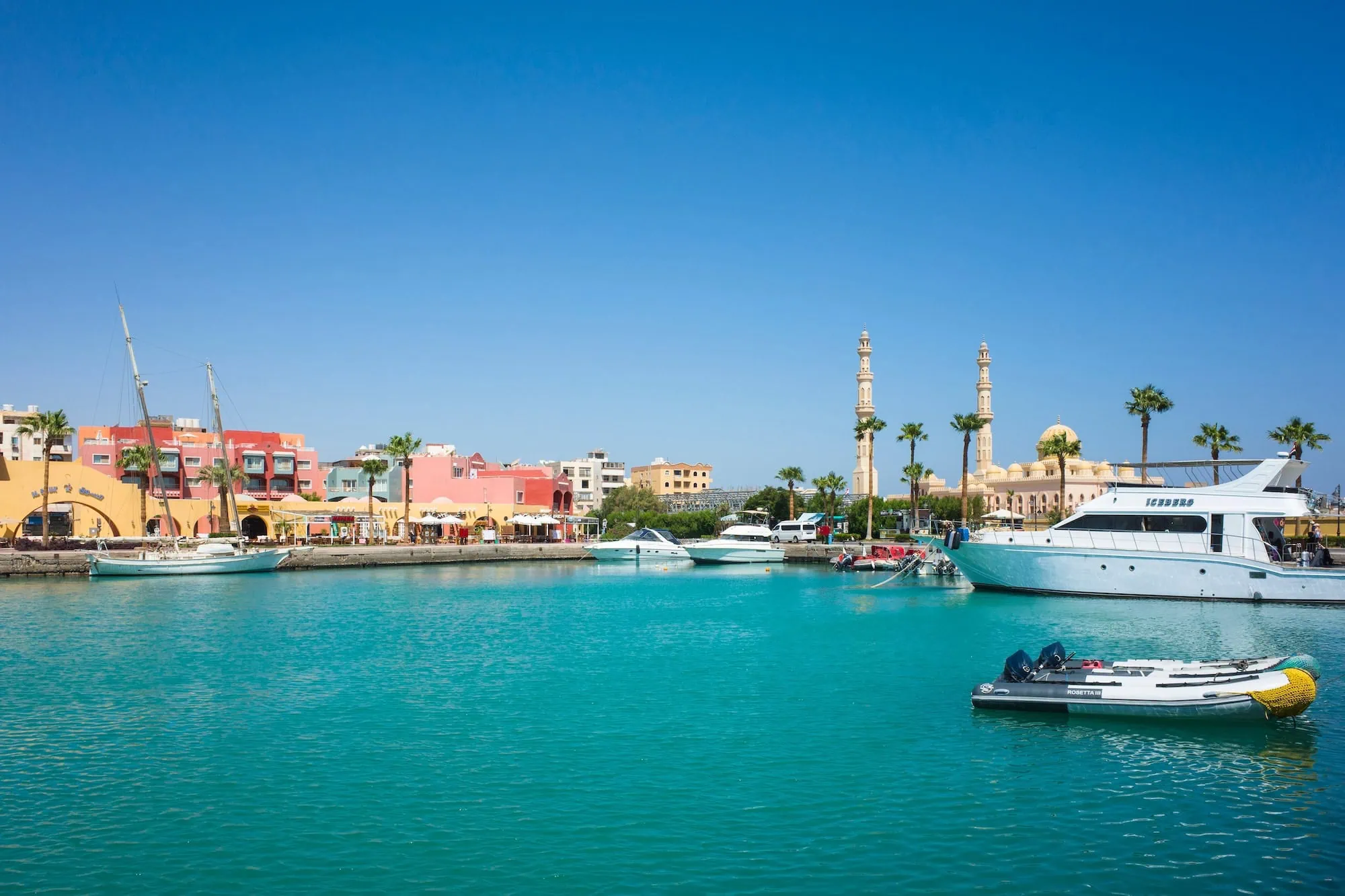Scenic view of Hurghada Marina with turquoise waters, colorful waterfront buildings, boats, and mosque minarets