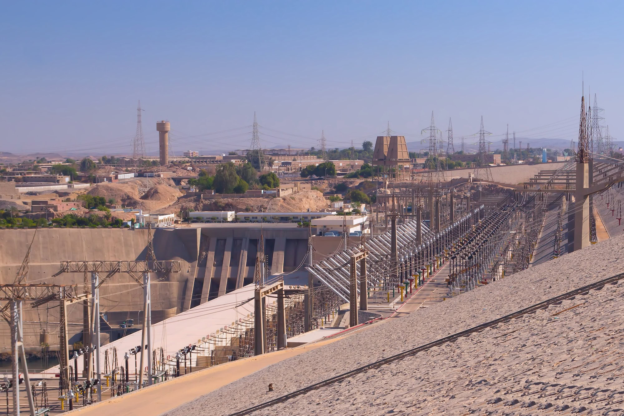 Aswan High Dam with power transmission towers and electrical infrastructure in desert landscape