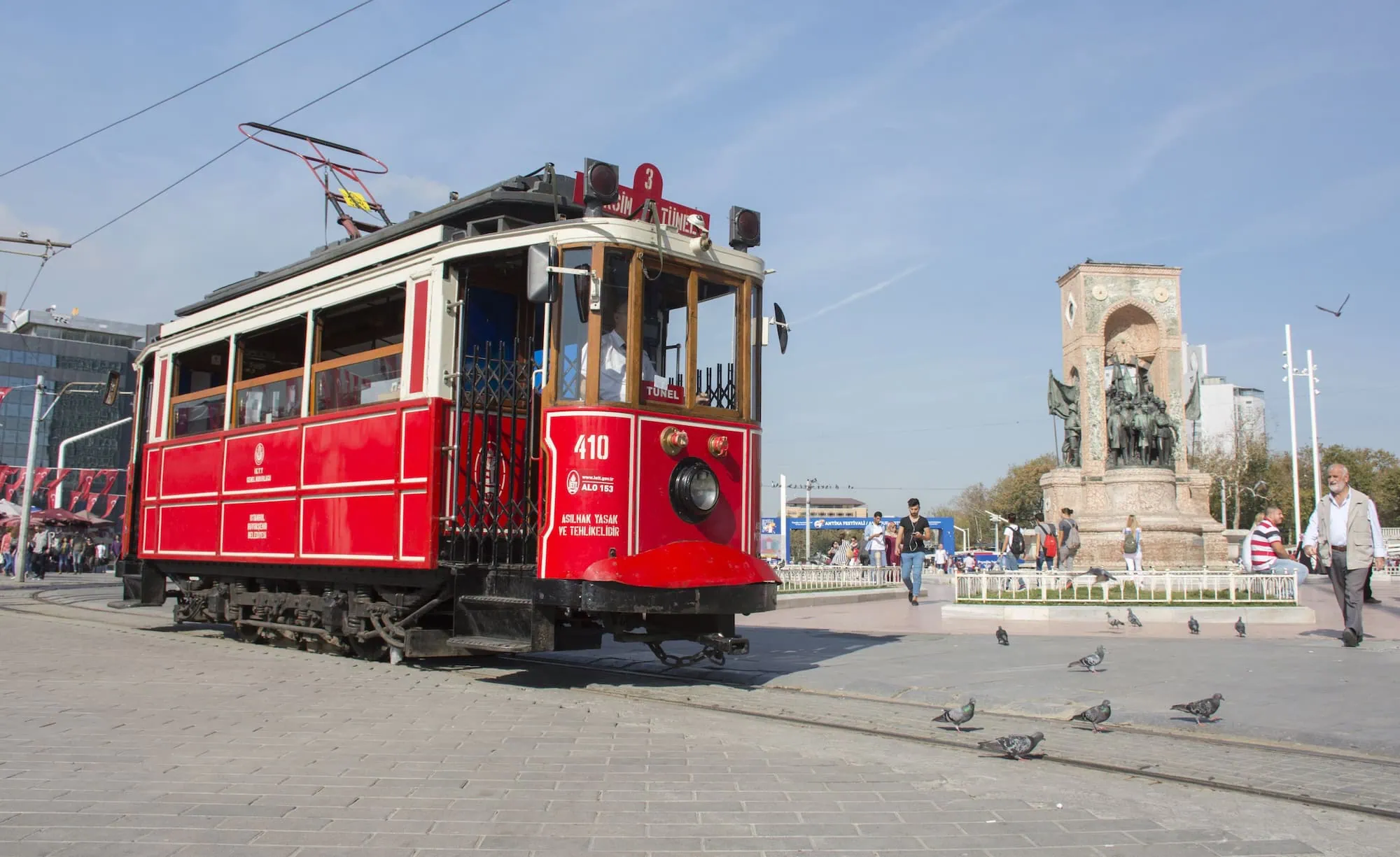 Historic red tram at Taksim Square with Republic Monument in background