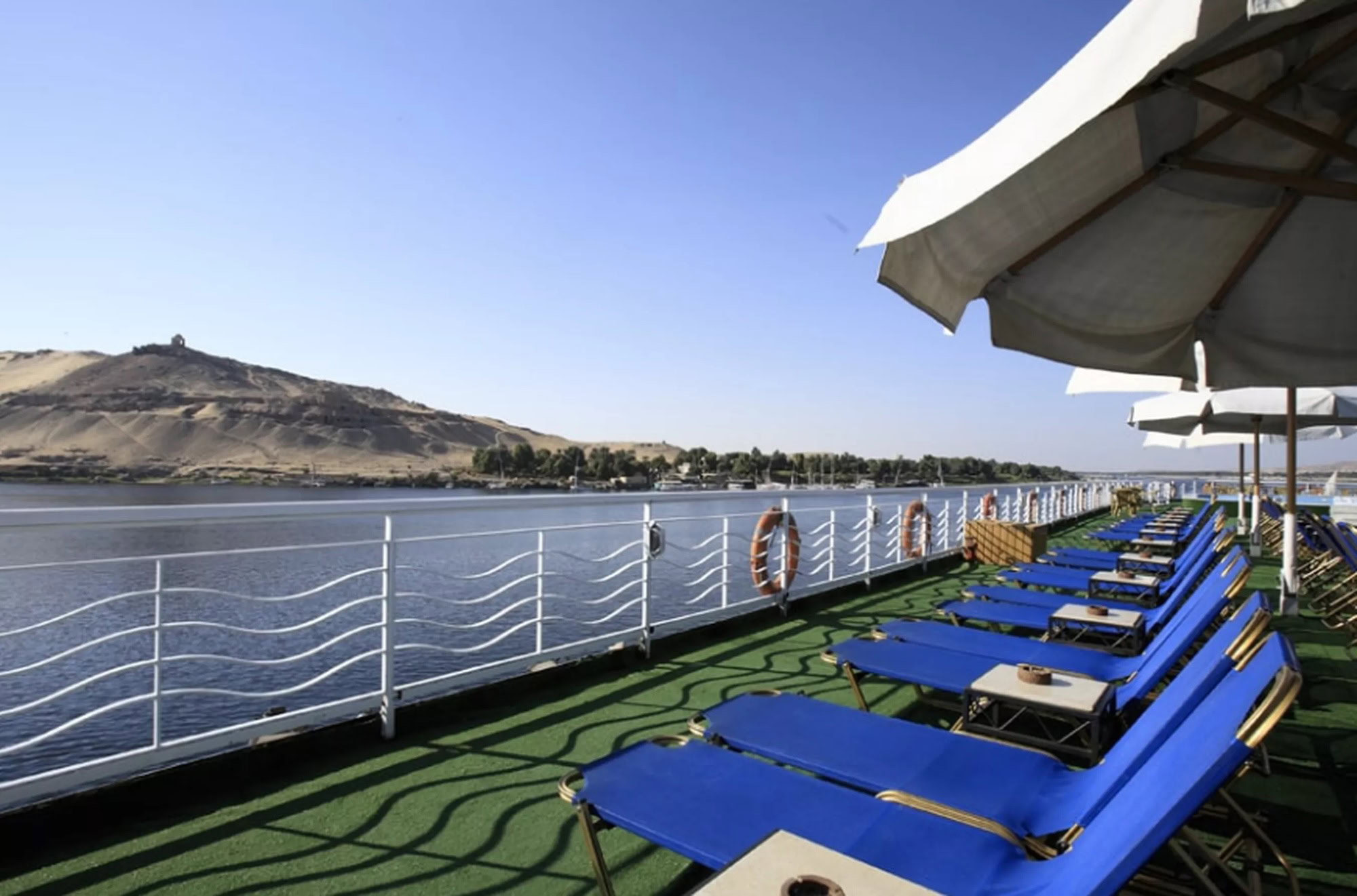 Sun loungers and shaded seating on a Nile cruise sundeck overlooking the river