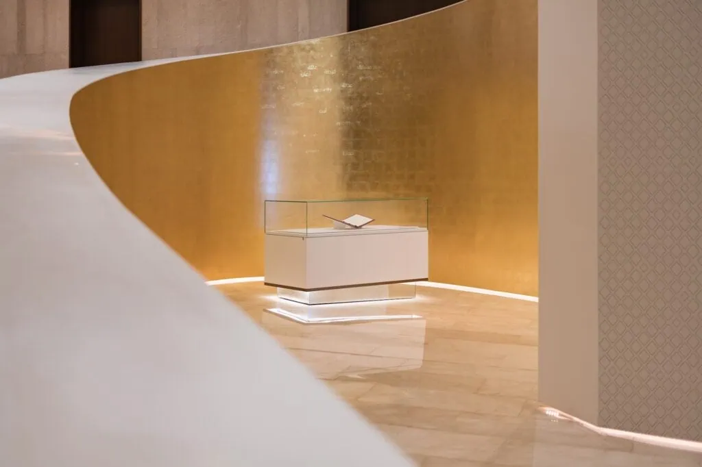 Etihad Museum display case with document exhibit set against a curved gold wall panel Dubai