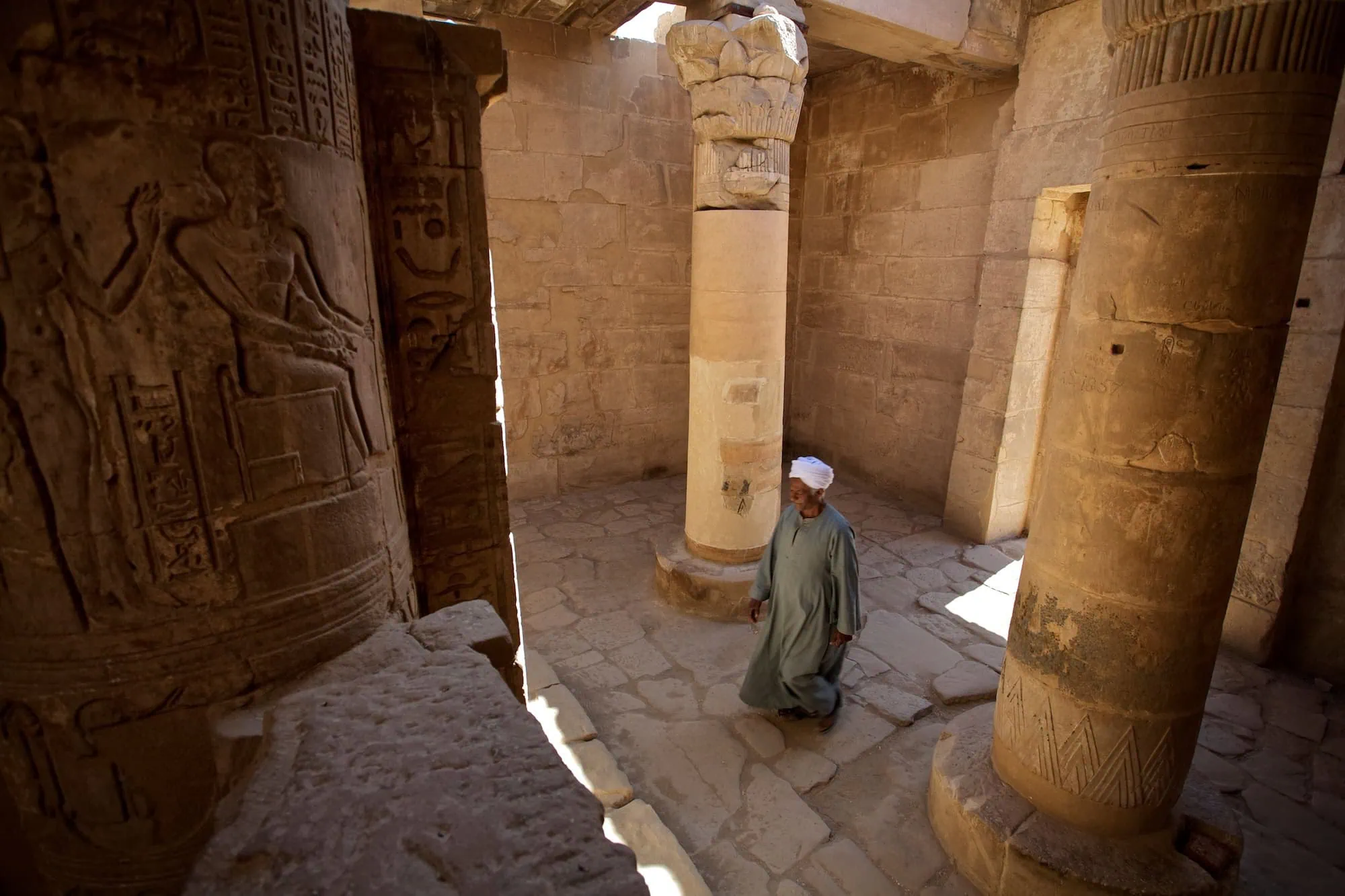 Persona en vestimenta tradicional dentro de templo egipcio antiguo con columnas y jeroglíficos