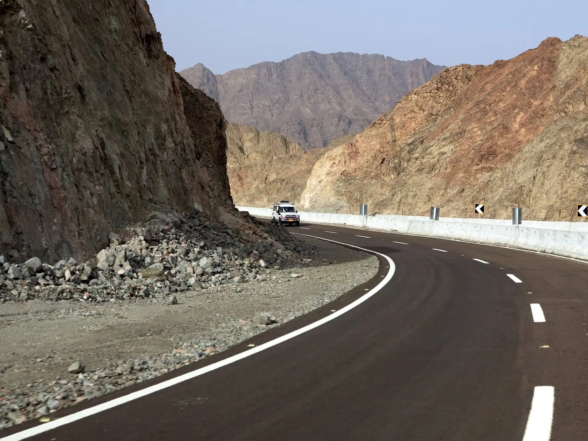 Jeep driving on winding mountain road through dramatic rocky Sinai Mountains terrain