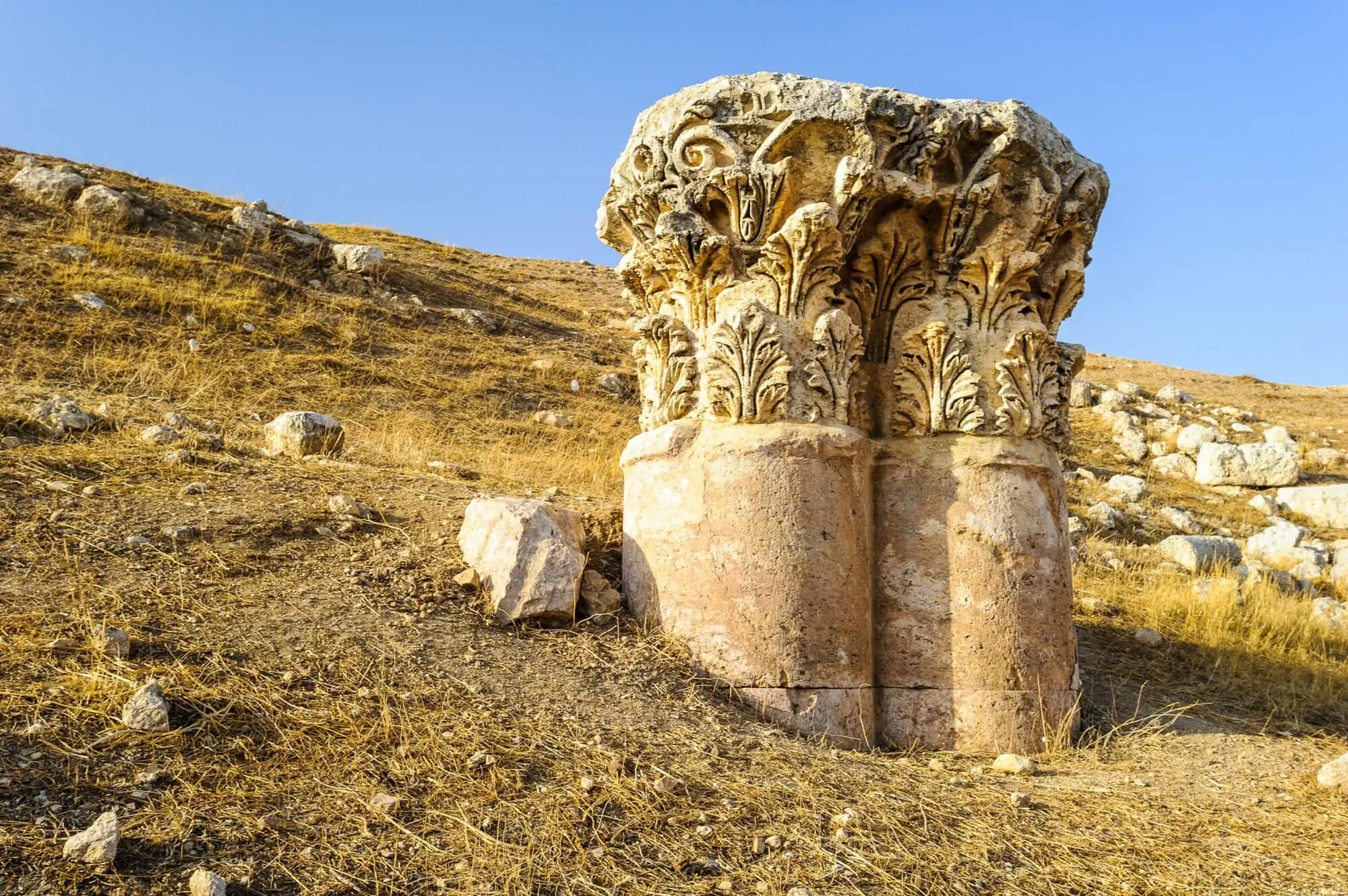 Ancient Roman Corinthian column capitals with intricate acanthus leaf carvings at Jerash ruins