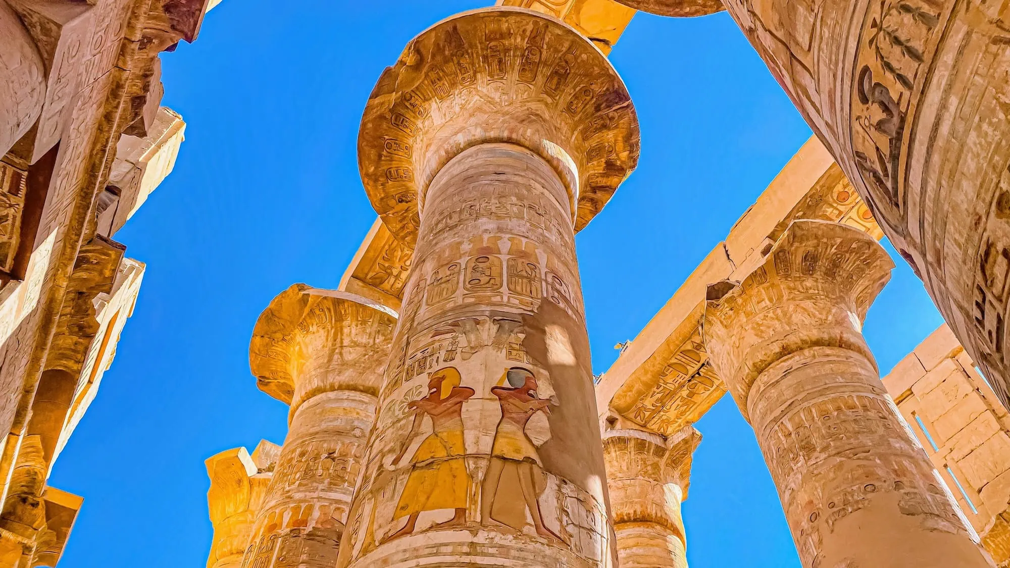 Ancient Egyptian stone columns with hieroglyphic carvings and papyrus-shaped capitals at Karnak Temple