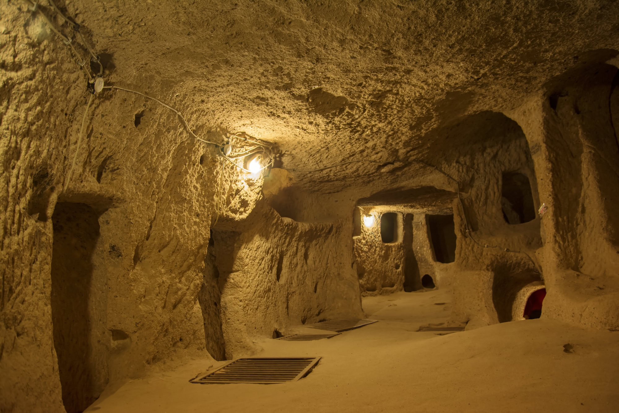 Underground cave tunnel with carved stone walls and electric lighting in Cappadocia