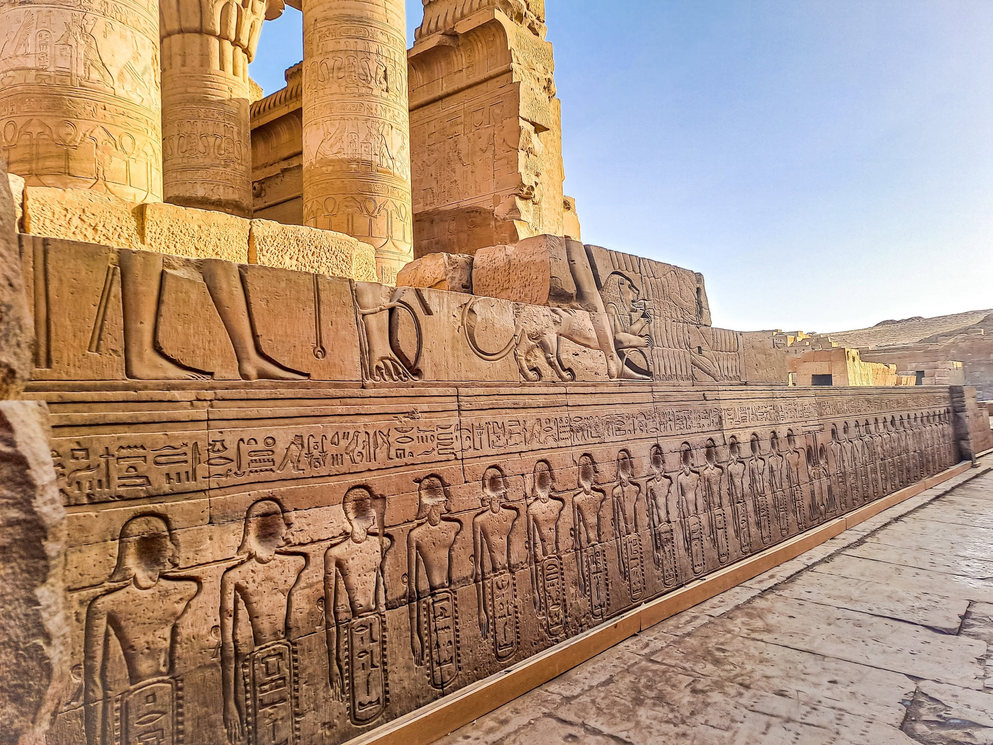 Ancient Egyptian hieroglyphic wall carvings at Kom Ombo Temple showing relief sculptures and human figures