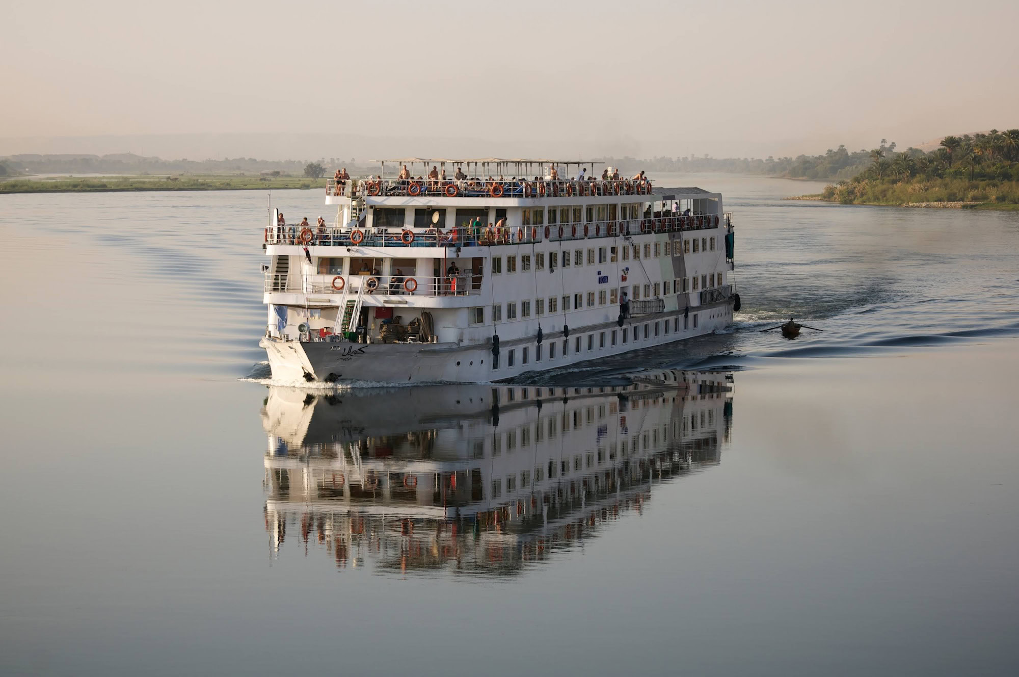 Nile River cruise ship sailing peacefully on the river with passengers on deck