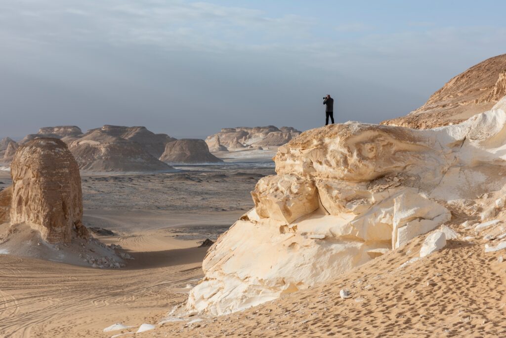 Landscape scenic view of desolate barren western desert in Egypt Valley of Agabat Obstacles at Farafra Oasis with geological rock formations and photographer