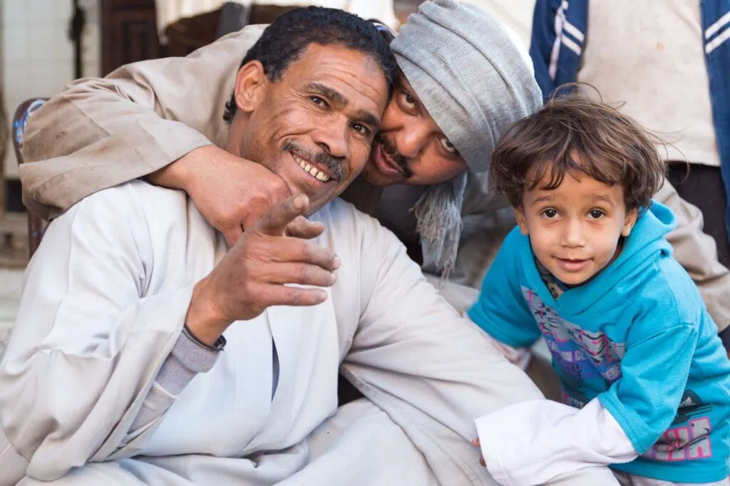 Local Egyptian people posing for a photograph among livestock and traditional market stalls at the Daraw camel and livestock market in Upper Egypt.