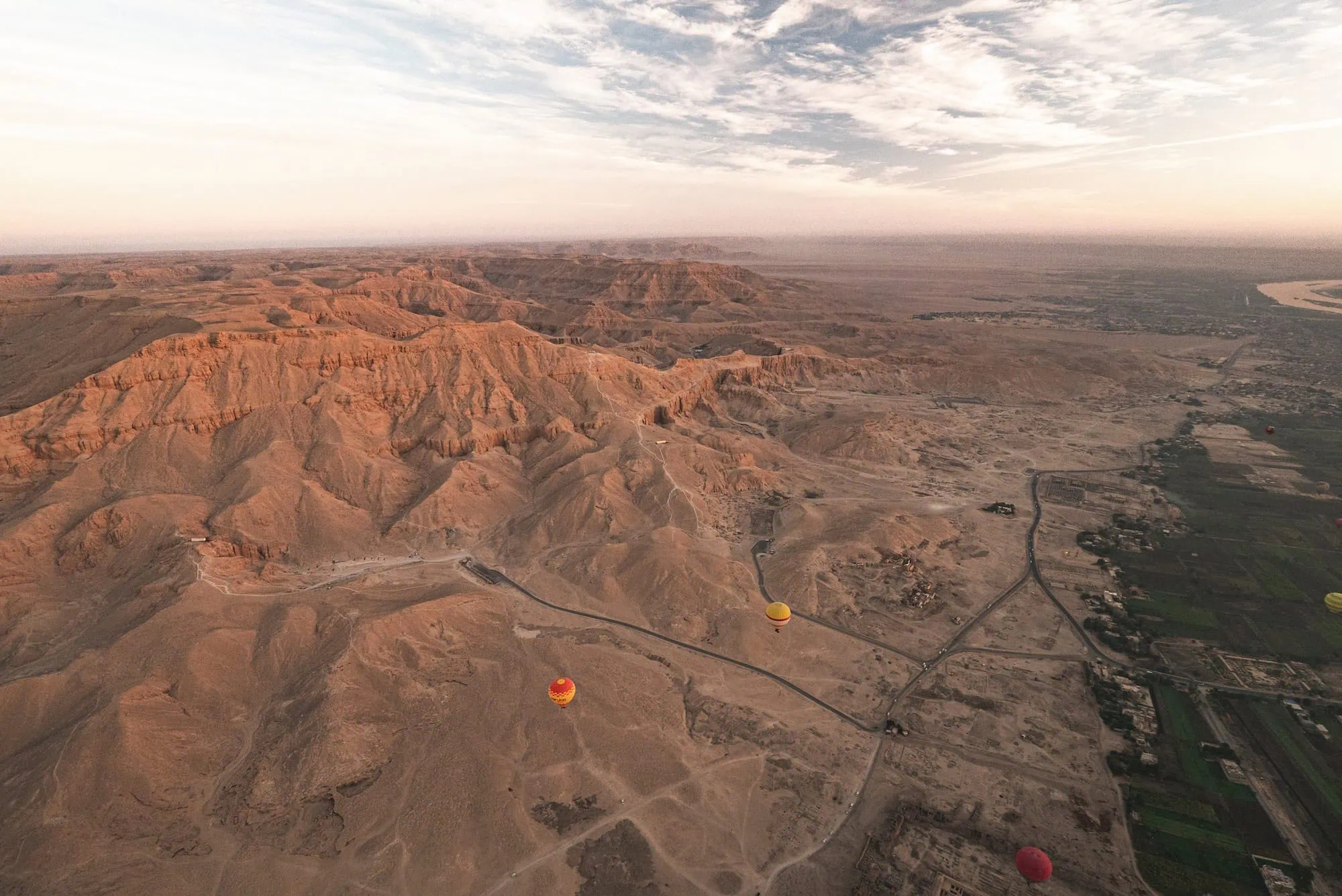 Hot air balloons floating over Valley of the Kings desert landscape in Egypt
