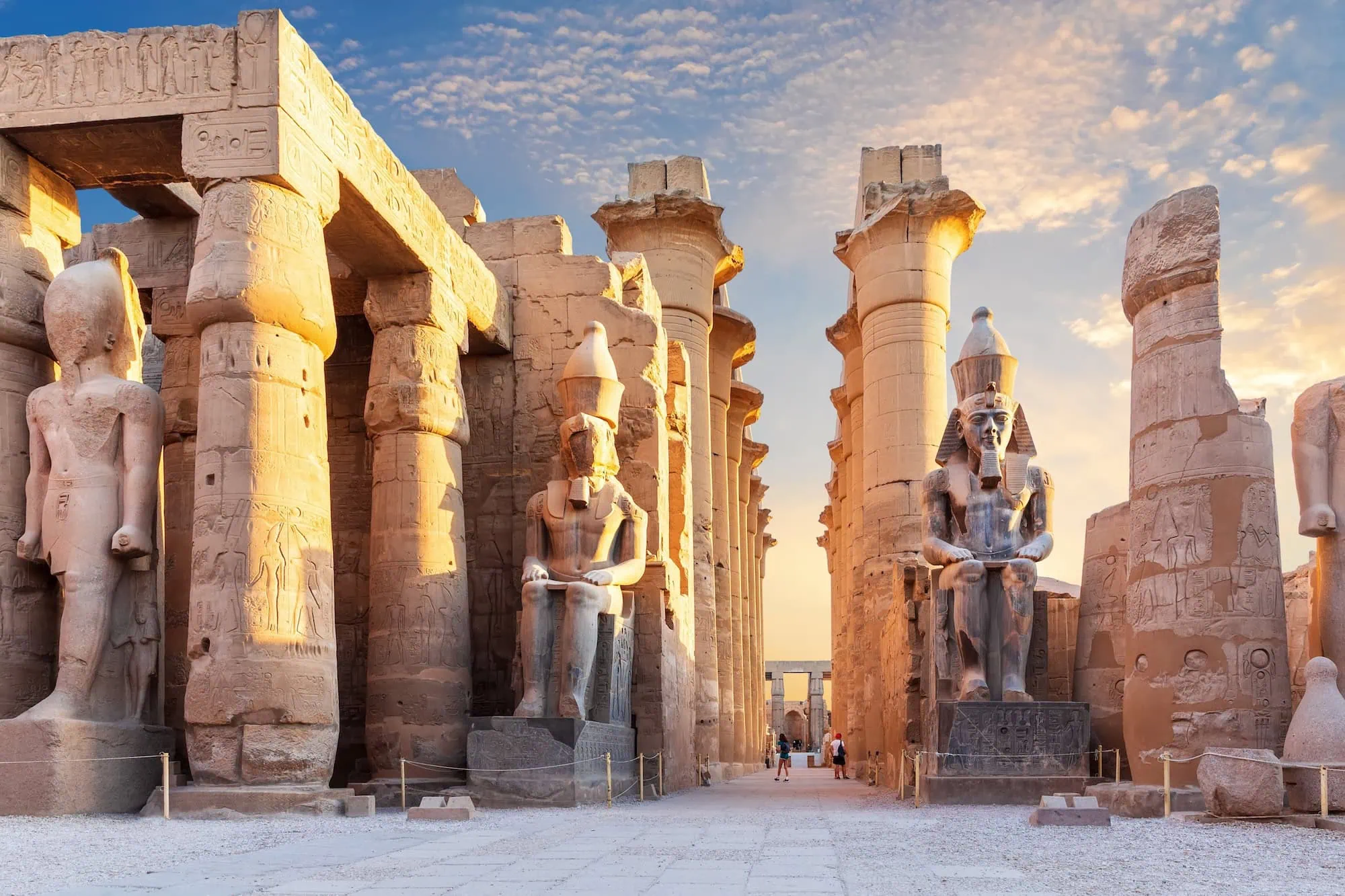 Ancient Egyptian Luxor Temple with towering papyrus columns and pharaoh statues in golden light