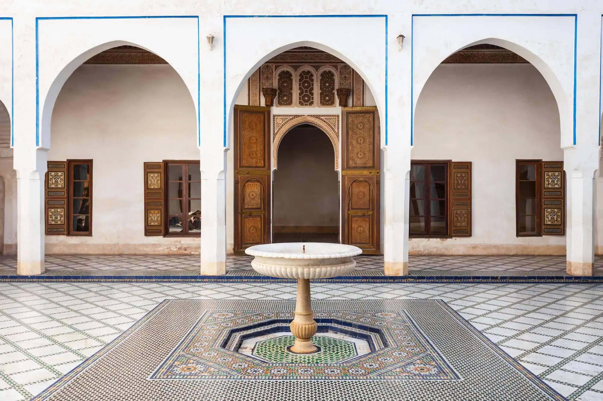 Interior courtyard of Bahia Palace with ornate Islamic architecture, geometric tilework, horseshoe arches and central fountain