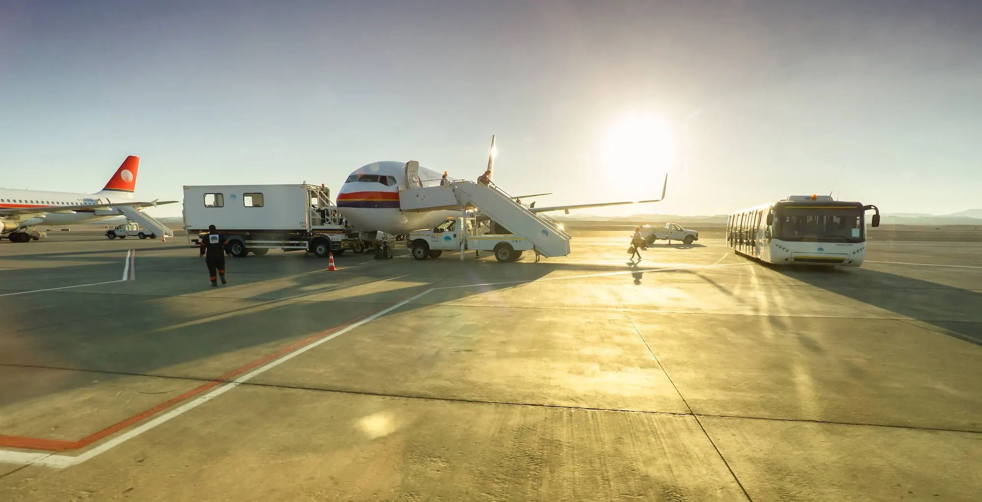Busy airport tarmac with aircraft and ground equipment during departure preparations