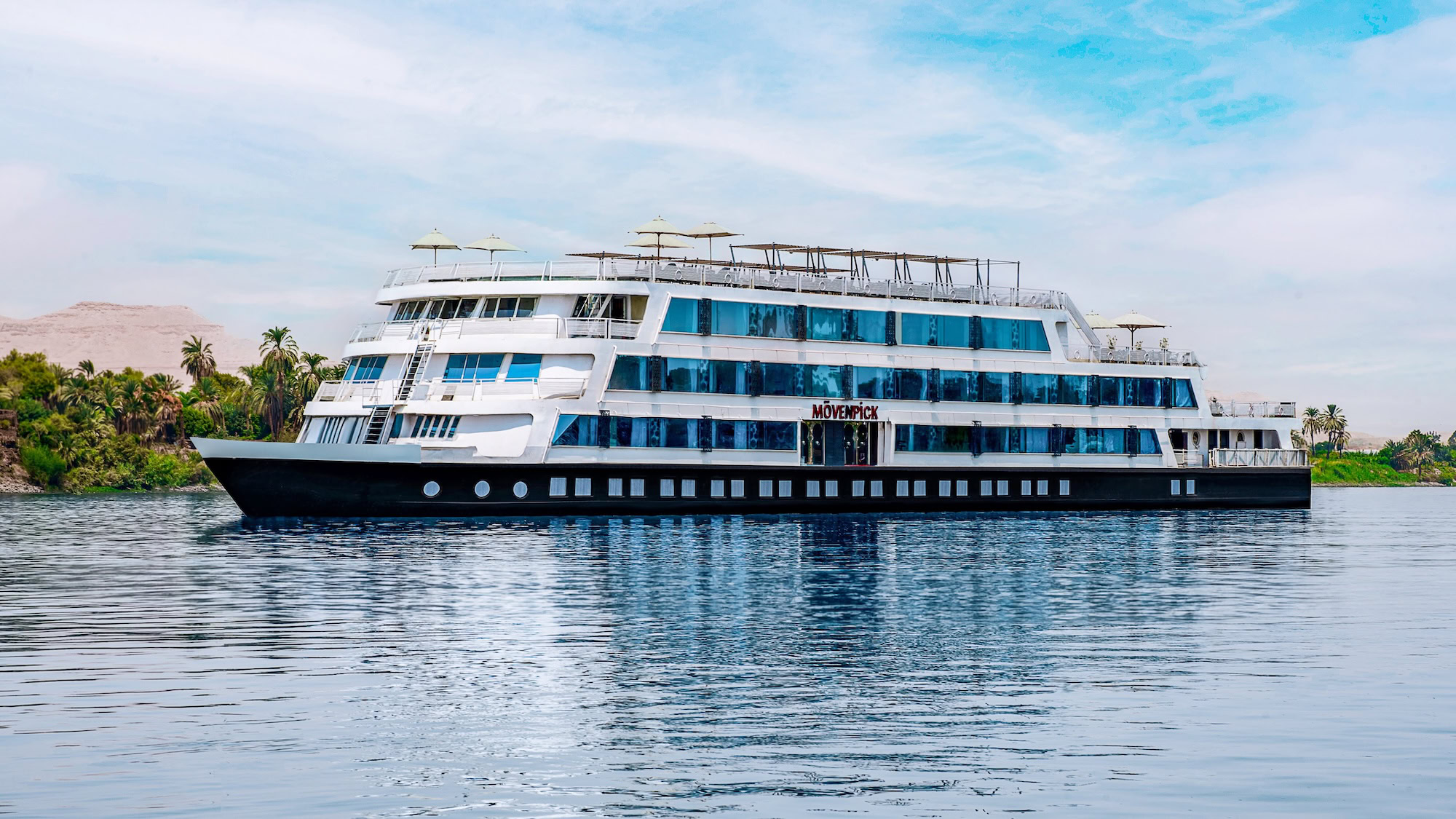 Navio de cruzeiro navegando pelo Rio Nilo com paisagem desértica