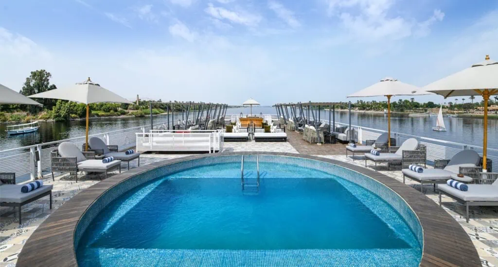 The outdoor swimming pool on the sun deck of the Mövenpick MS Darakum Nile cruise vessel, with a view over the Nile River, Egypt.