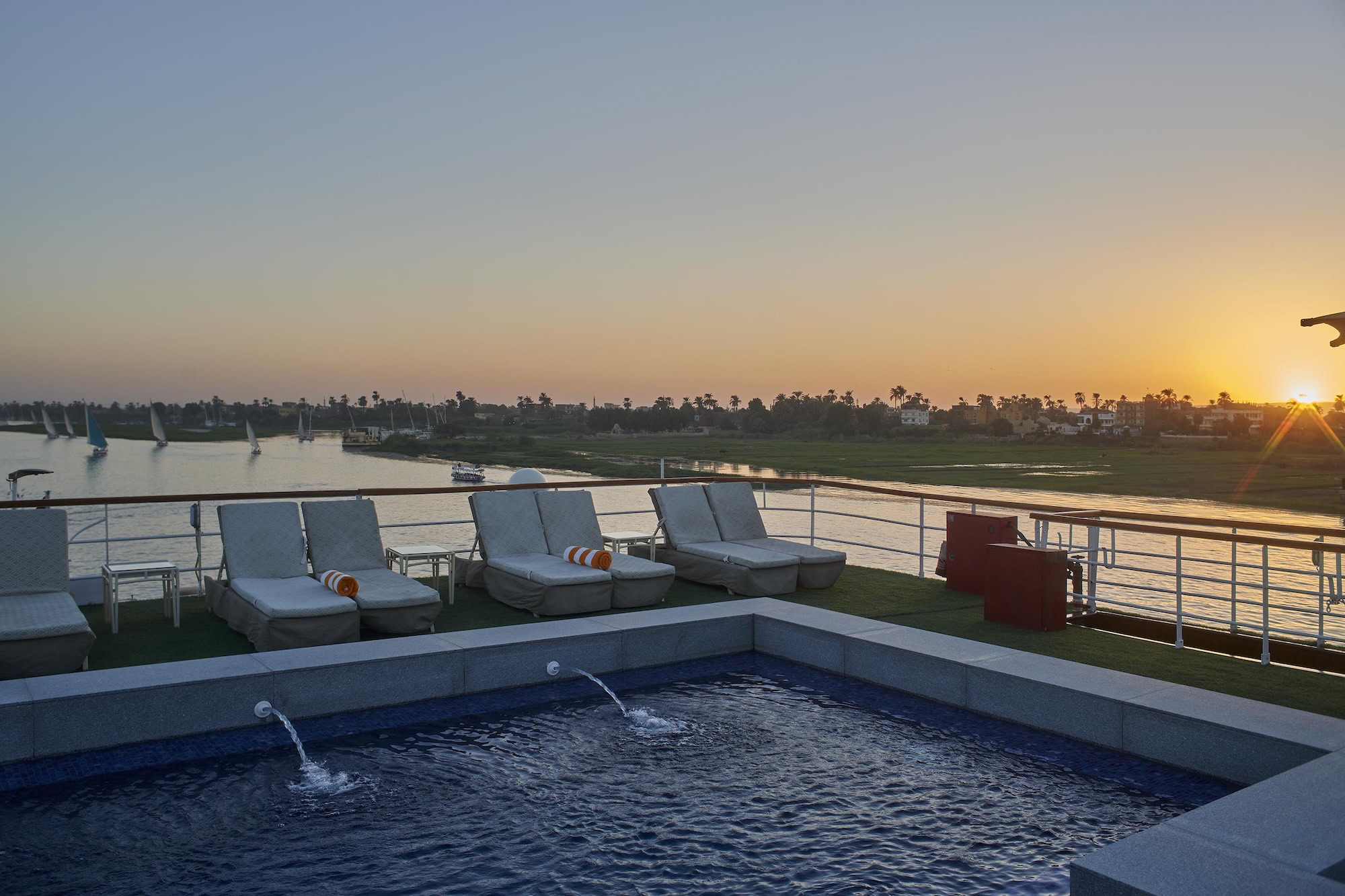 Nile River cruise ship pool deck with lounge chairs and traditional sailboats