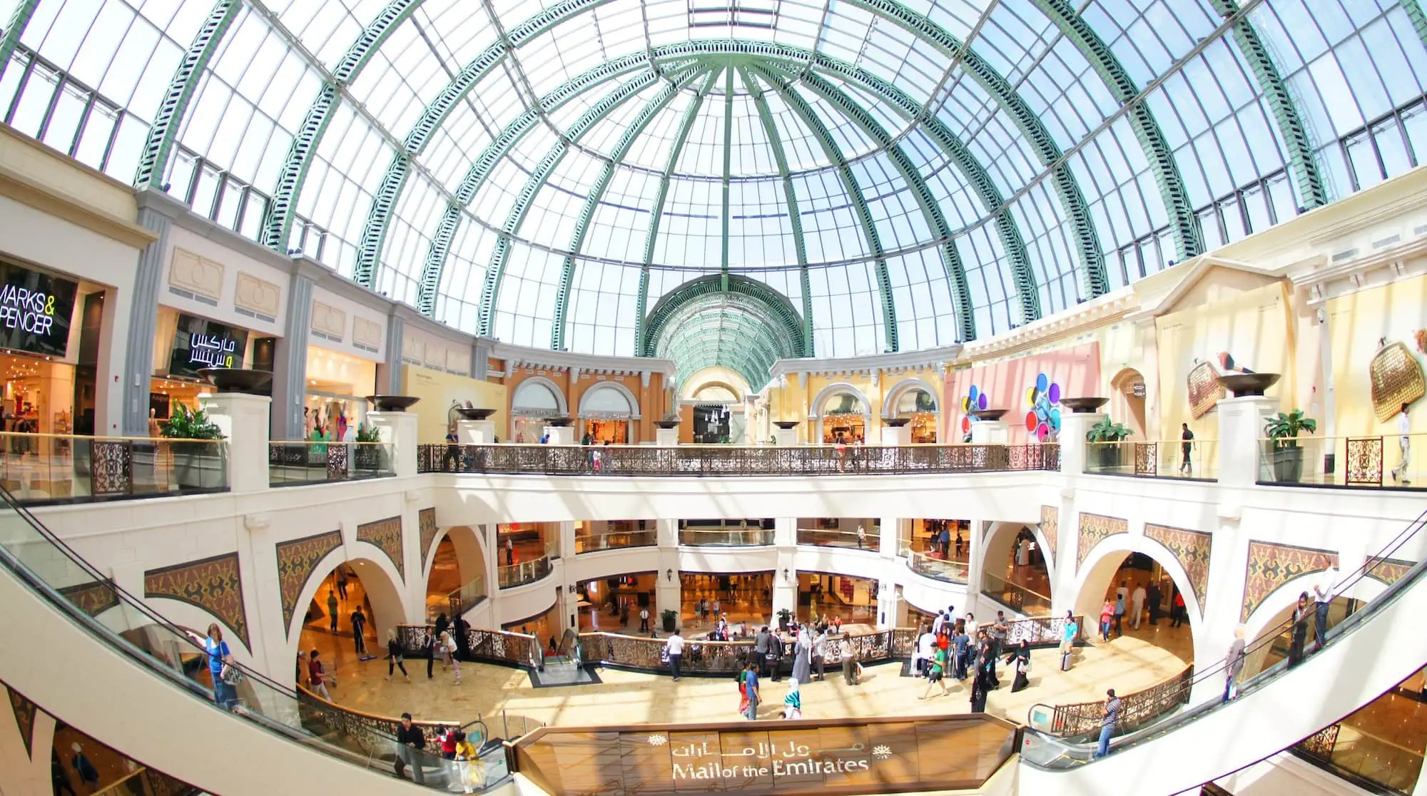 Luxurious multi-level shopping mall interior with glass dome ceiling and marble flooring