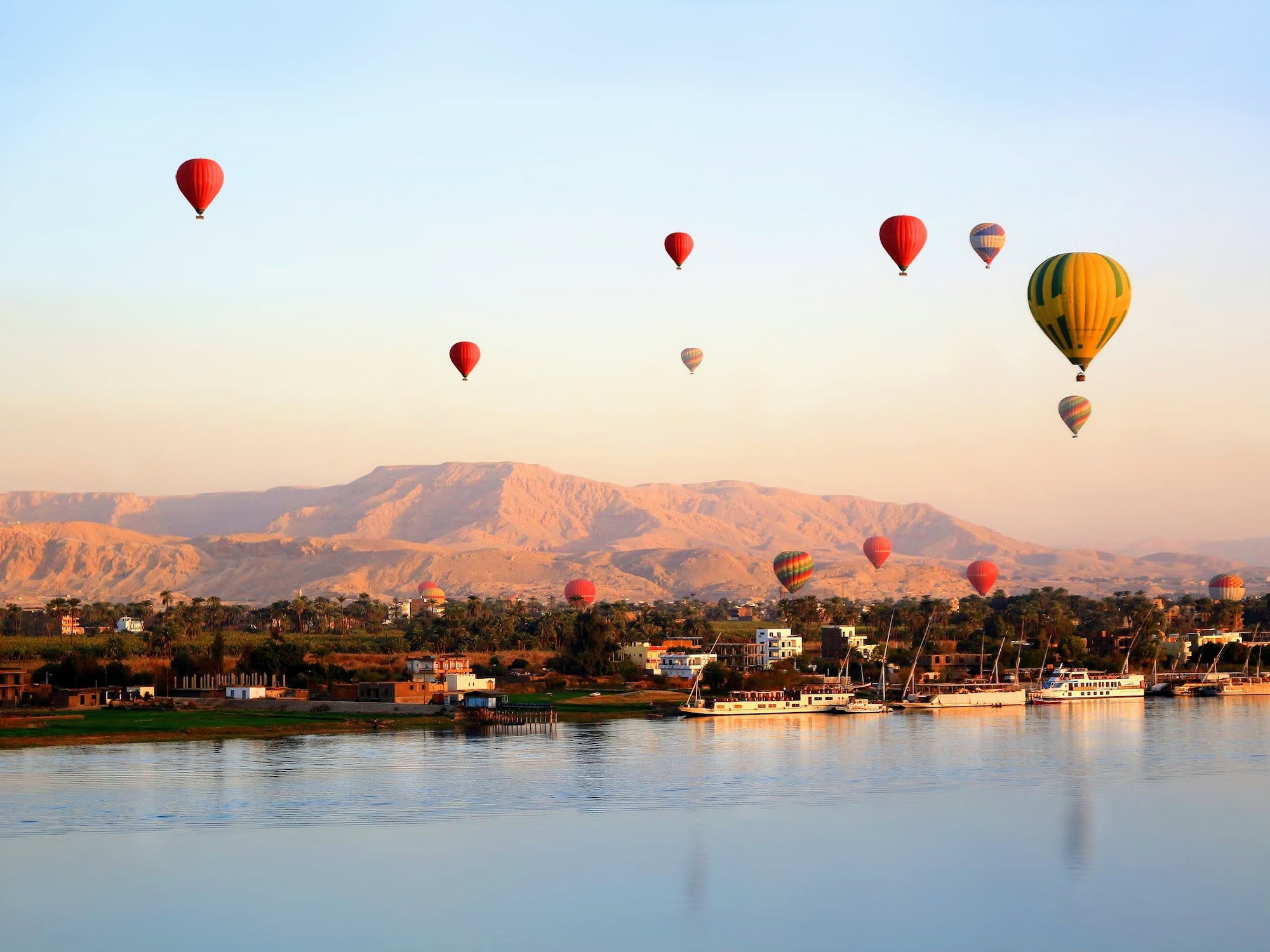 Many Hot air balloons floating over the Nile River in Luxor at sunrise