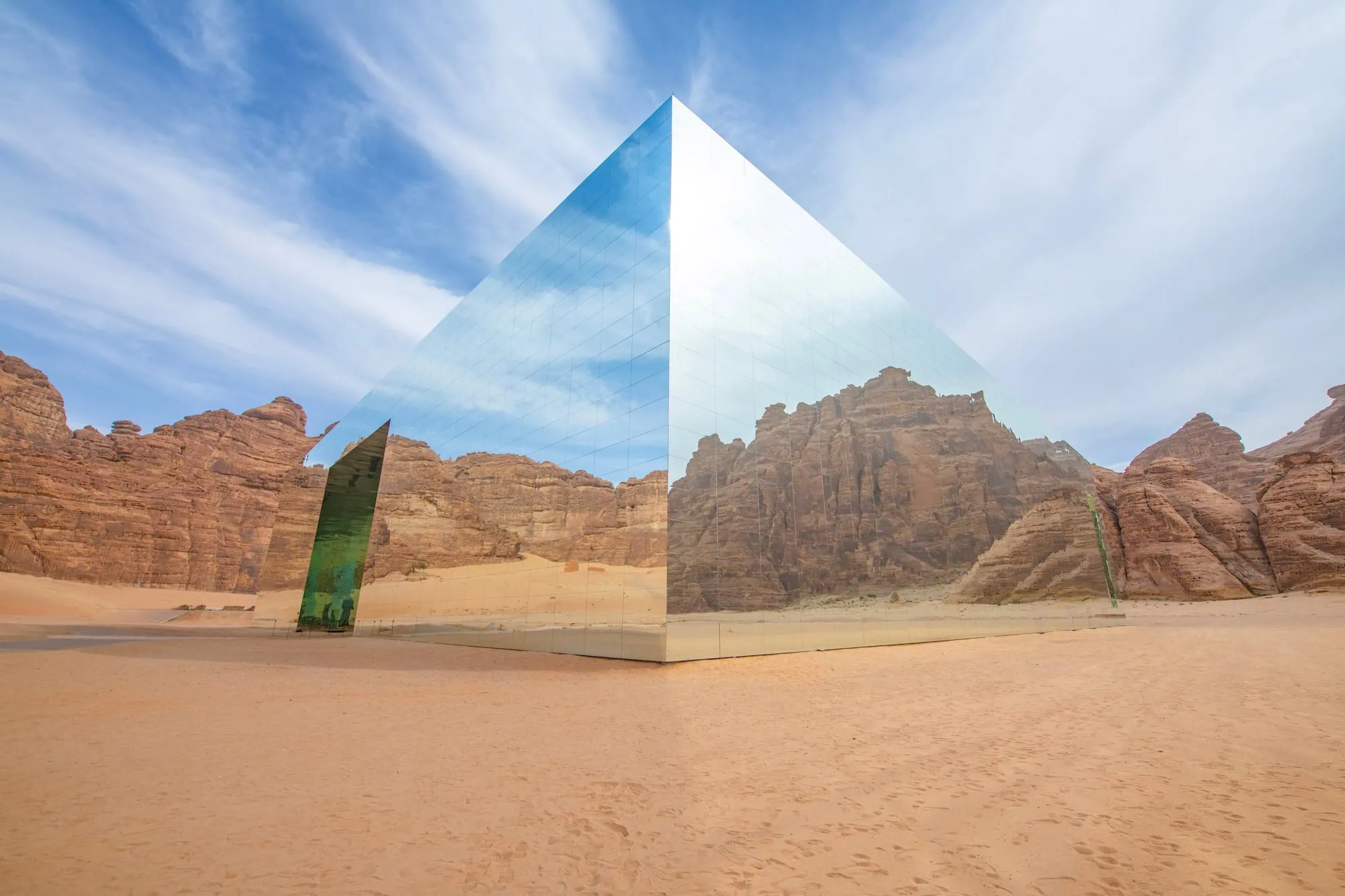 The Maraya concert hall in AlUla, Saudi Arabia — a mirrored cube reflecting the surrounding sandstone desert landscape, holding the Guinness record as the world's largest mirrored building