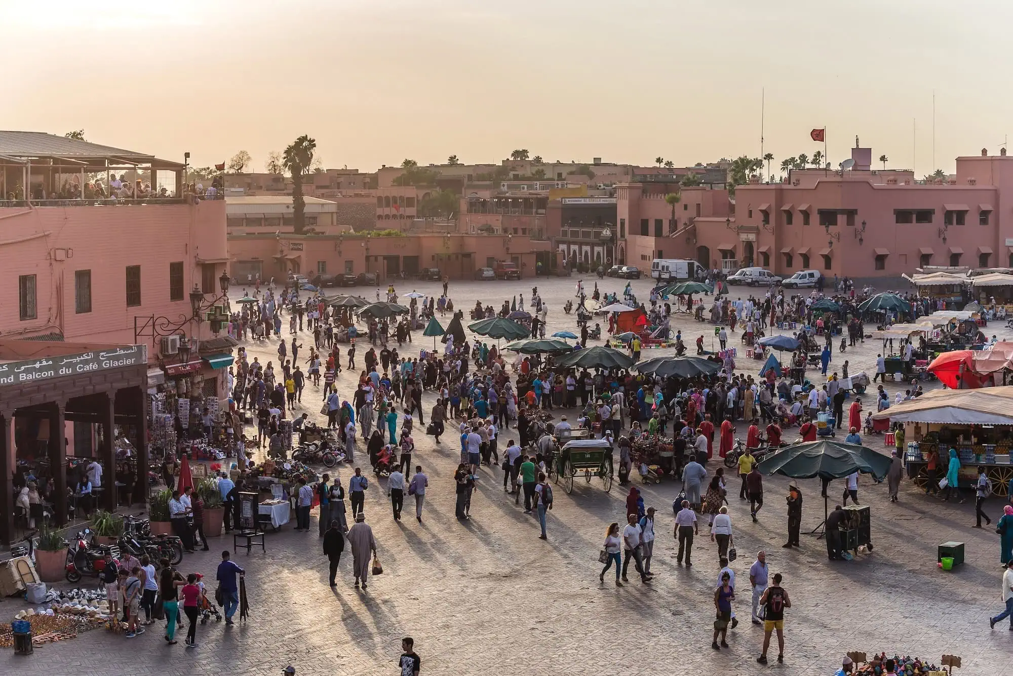 Bustling Djemaa el-Fna square in Marrakech with crowds, market stalls and traditional red buildings