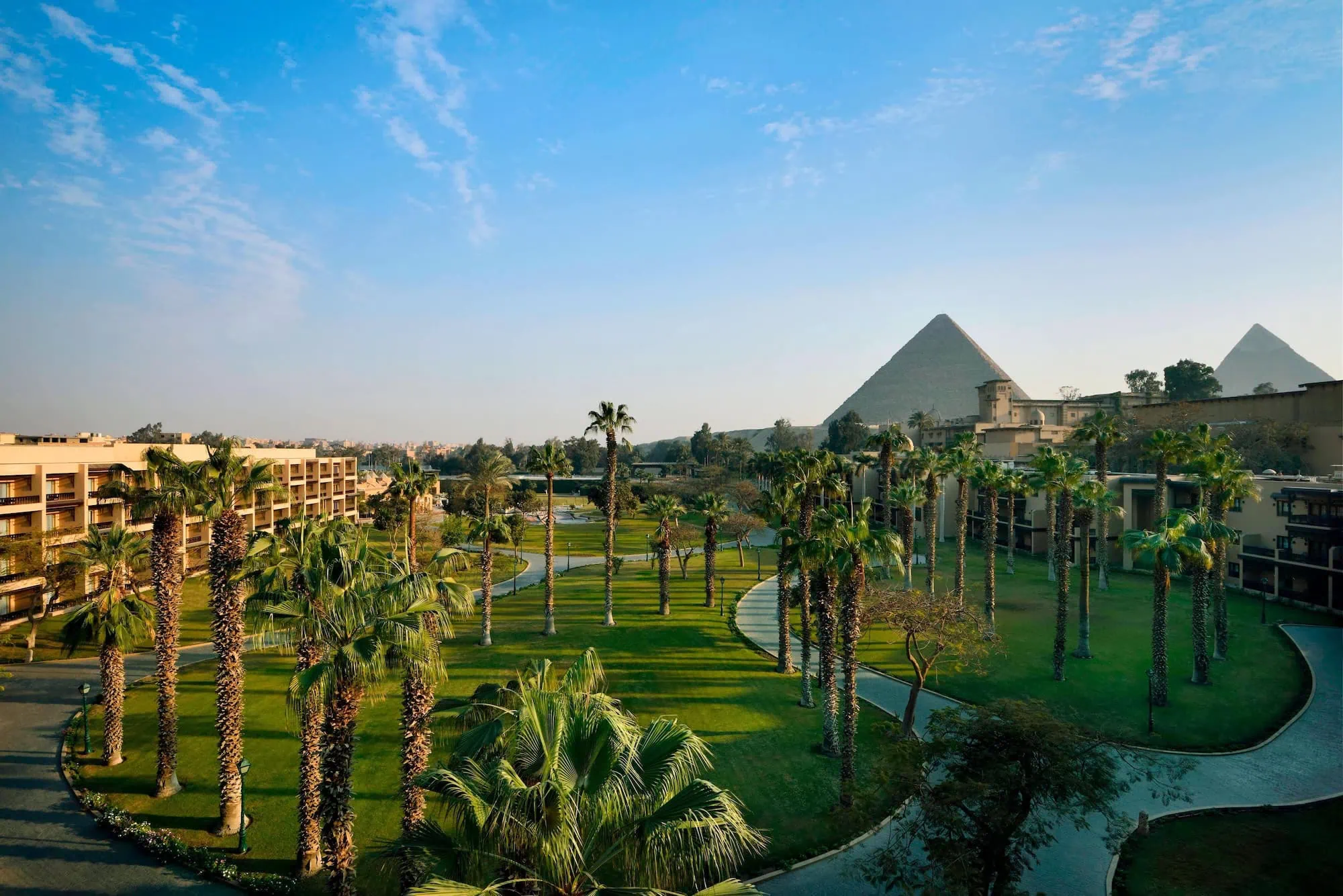 Luxurious hotel resort in Cairo with landscaped gardens and the Giza pyramids visible in the background