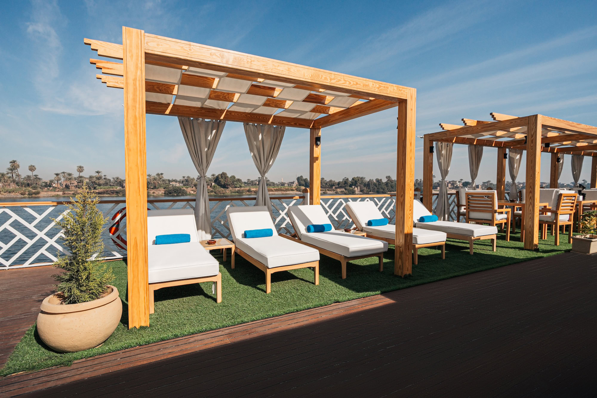 Sun loungers under a pergola with white curtains on a Nile River cruise ship deck