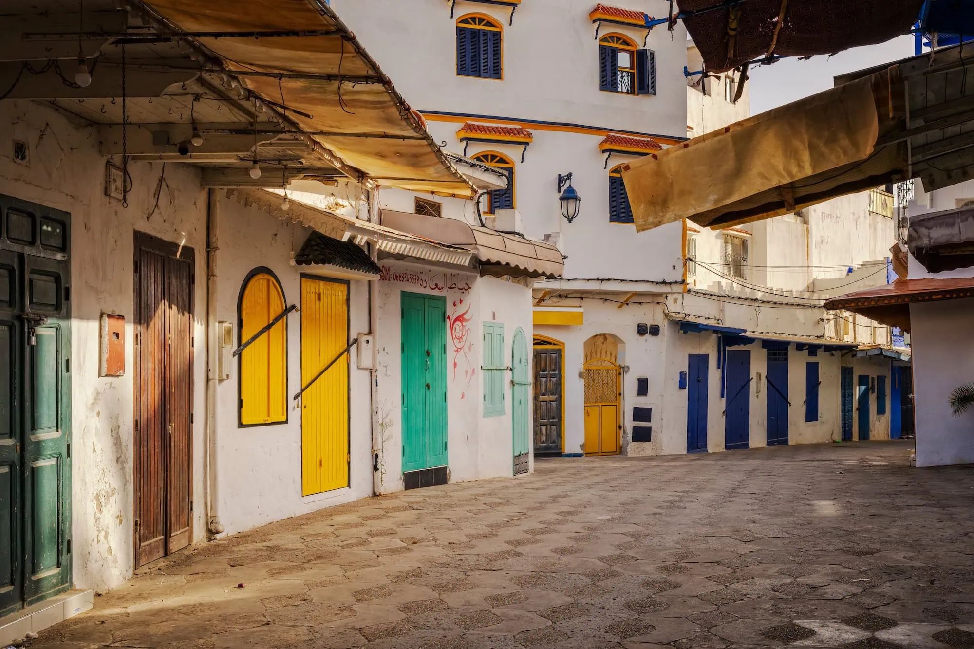 Colorful courtyard in Assilah Medina with traditional Moroccan architecture and bright painted doors