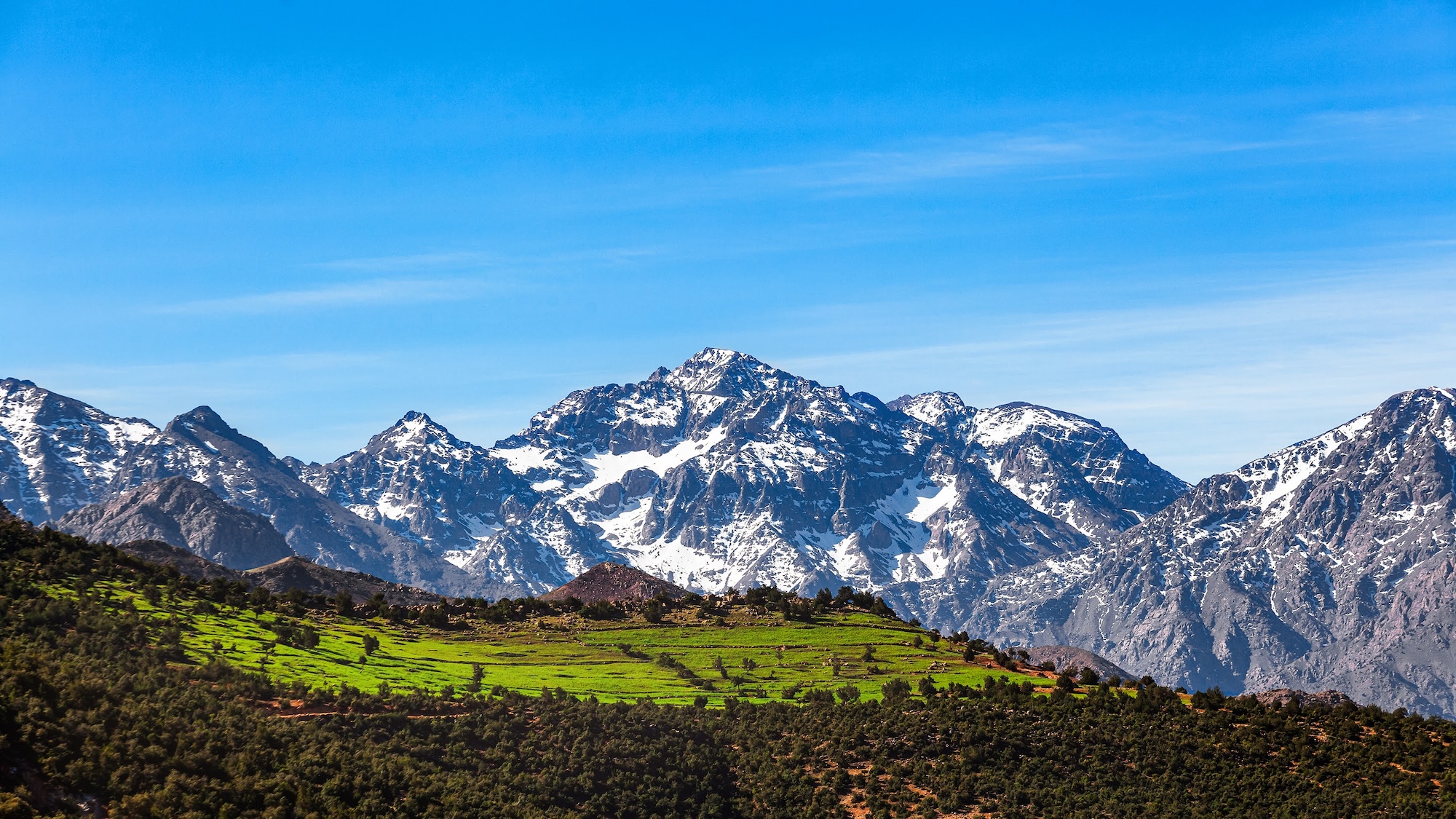 Snow-capped High Atlas Mountains with terraced green valleys and agricultural fields