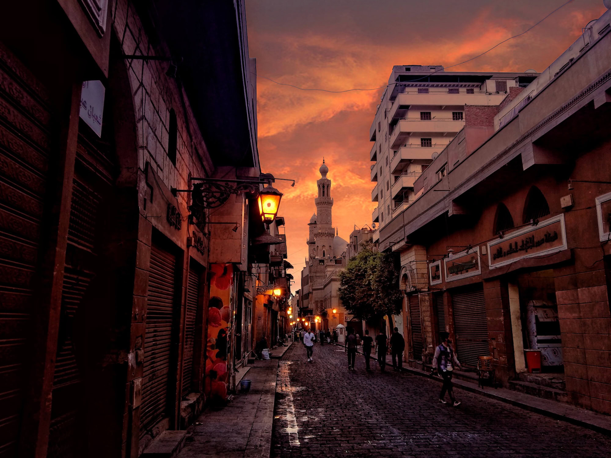 Cairo street scene showing shuttered storefronts and mosque minaret in Islamic historic district