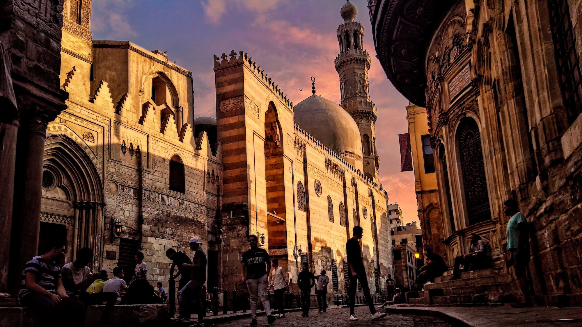 Tourists walking through Islamic Cairo historic district with mosque and minaret