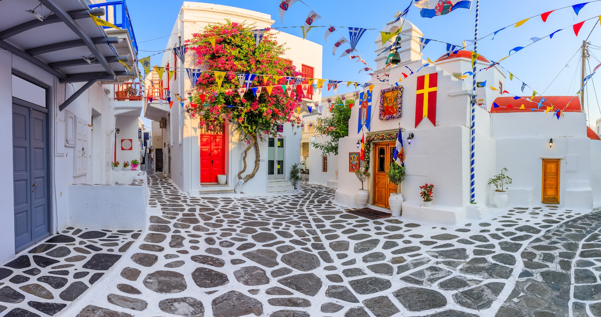Traditional Greek island village square with white buildings and colorful festive decorations