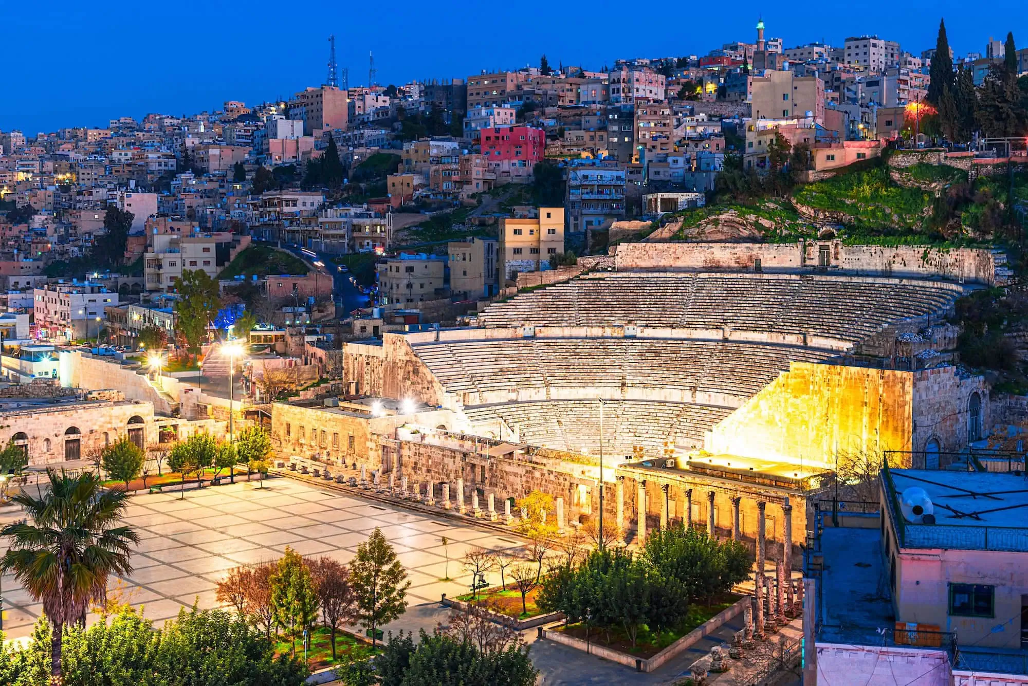Roman Theater in Amman illuminated at night with golden lighting and city backdrop